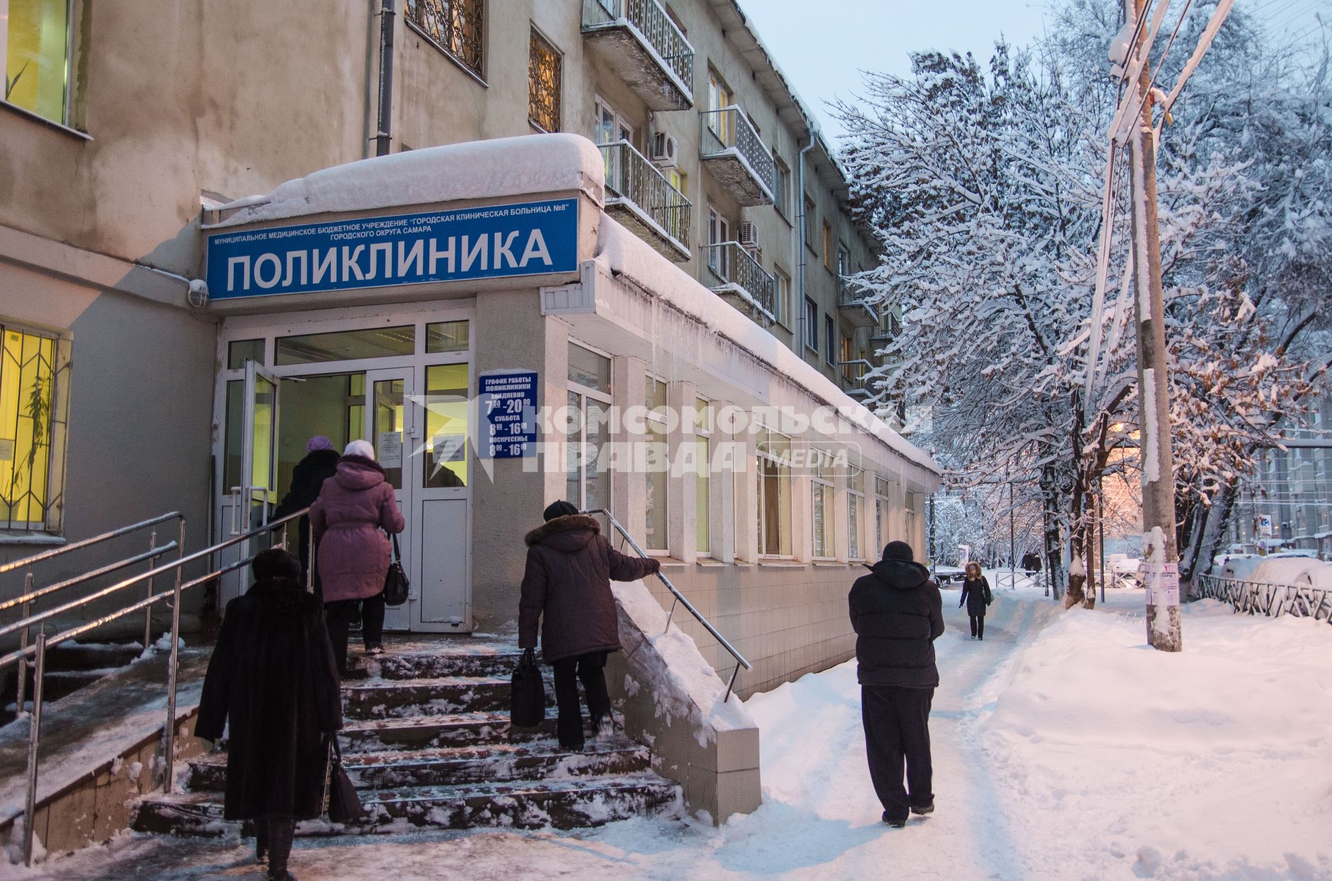 Люди заходят в городскую поликлинику.