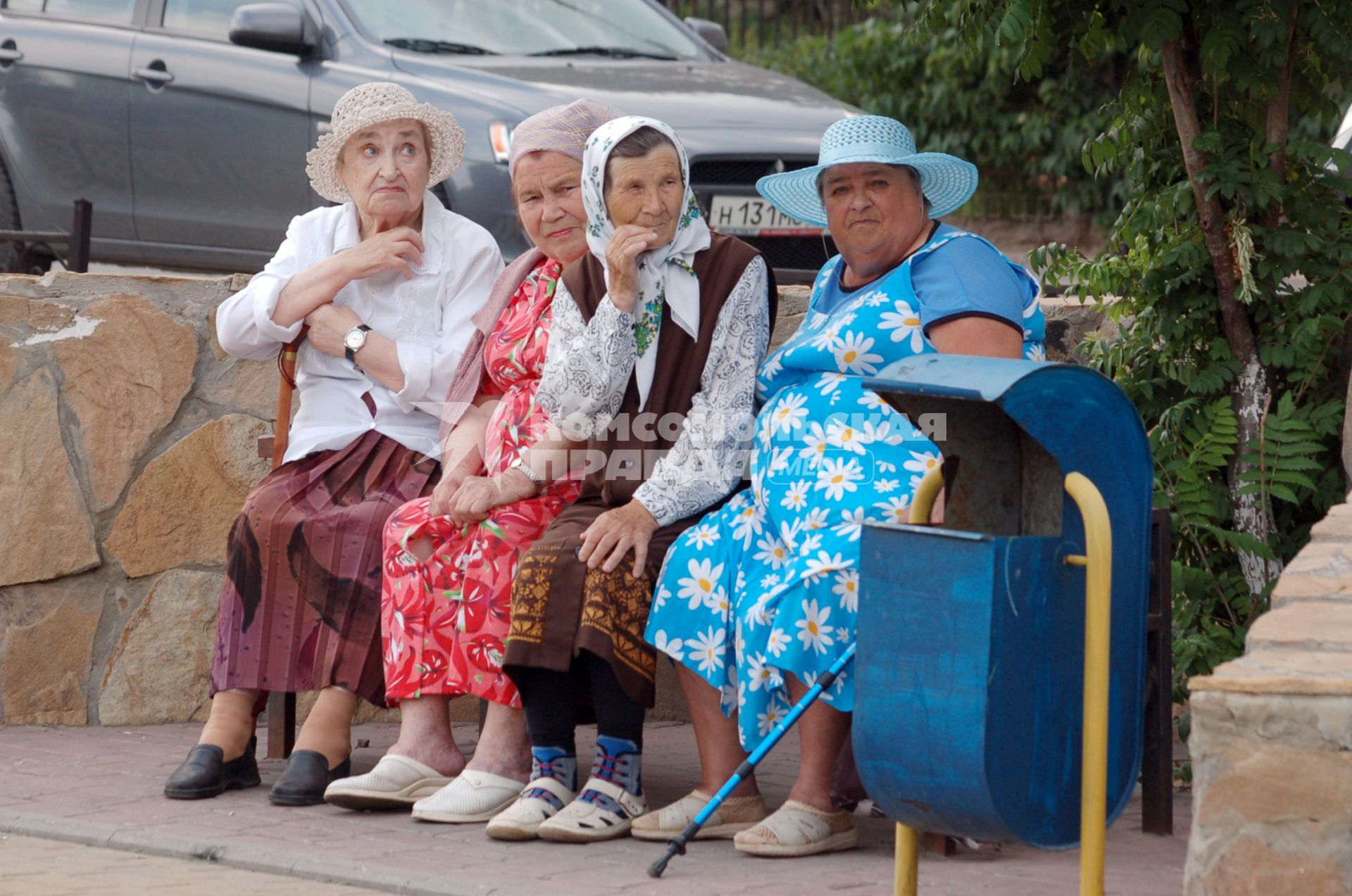 Нарядные пенсионерки сидят летом на лавочке.
