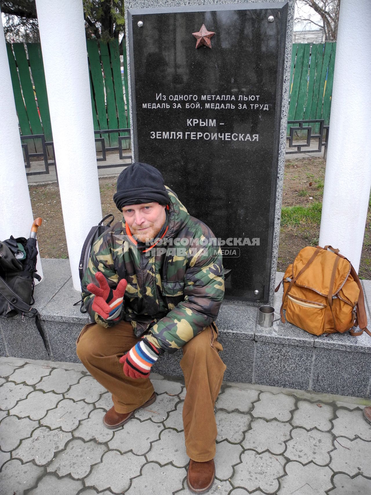 Беспорядки у здания парламента Крыма в Симферополе. Мужчина у памятника с надписью: `Из одного металла льют медаль за бой, медаль за труд. Крым - земля героическая`.