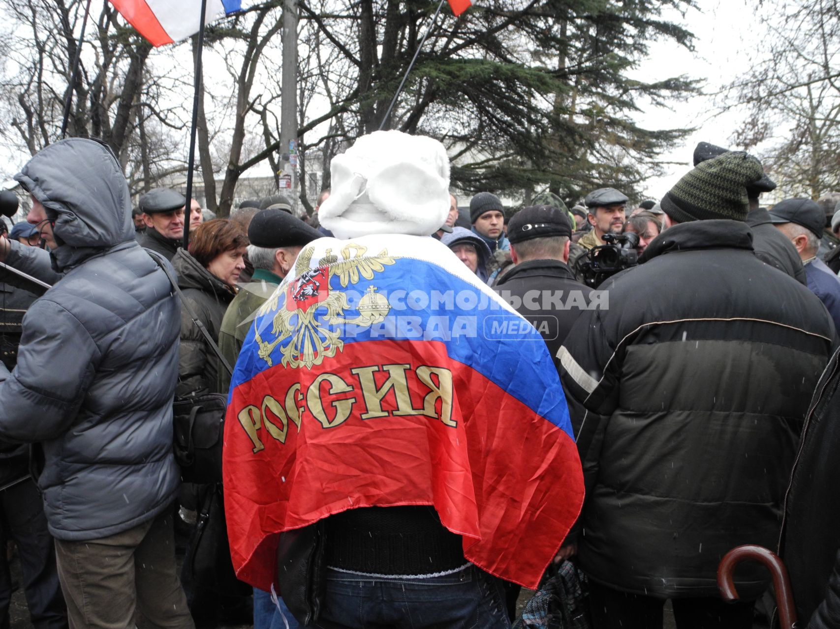 Митинг у здания парламента Крыма в Симферополе. Человек с российским флагом на митинге.