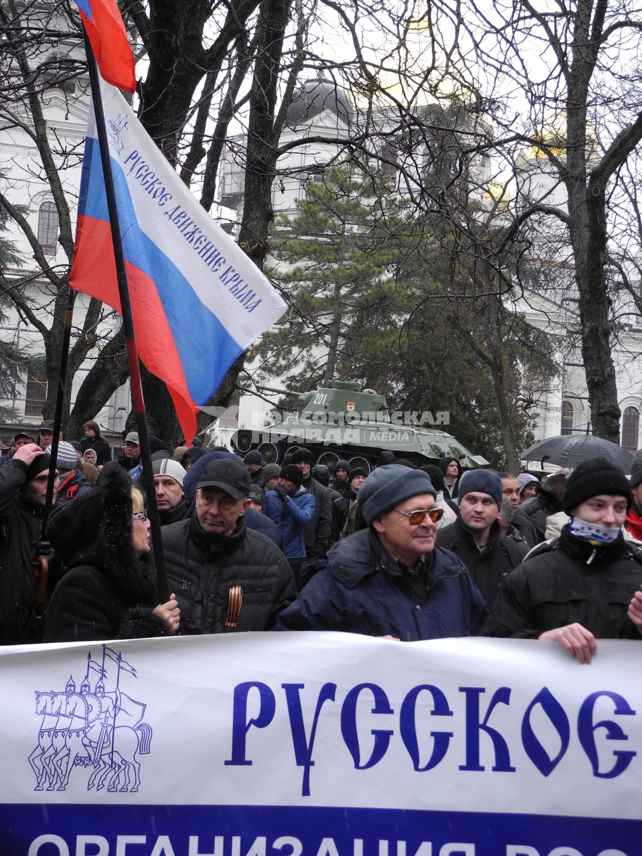 Митинг у здания парламента Крыма в Симферополе. Митингующие с российским флагом и плакатом на фоне памятника танку `т-34`.