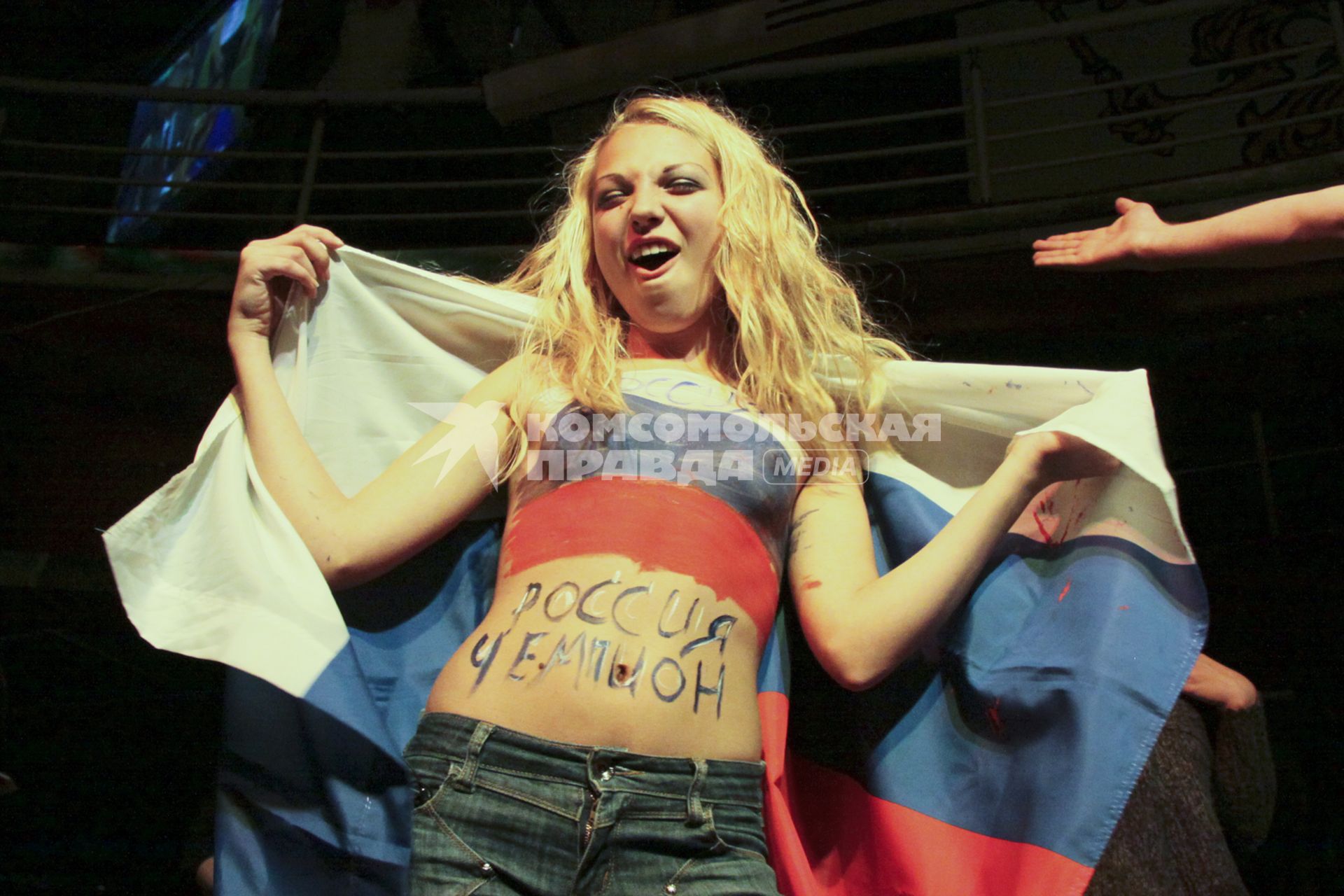Футбольный матч `Россия - Словения` Девушка раскрашенная в цвет российского флага с российским флагом на плечах болеет за сборную России.