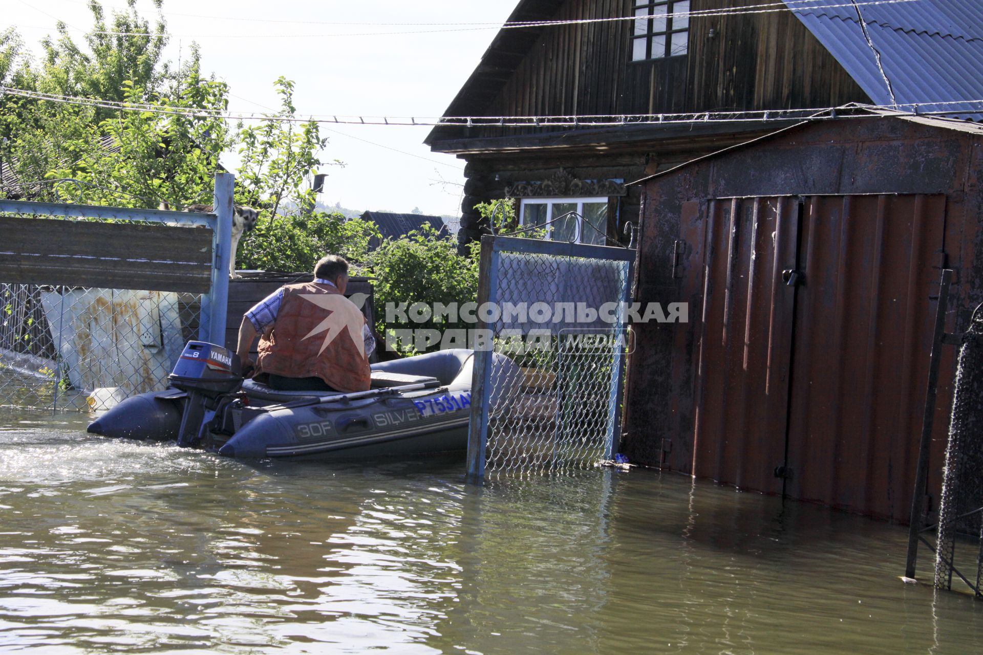 Мужчина на моторной надувной лодке около своего дома.