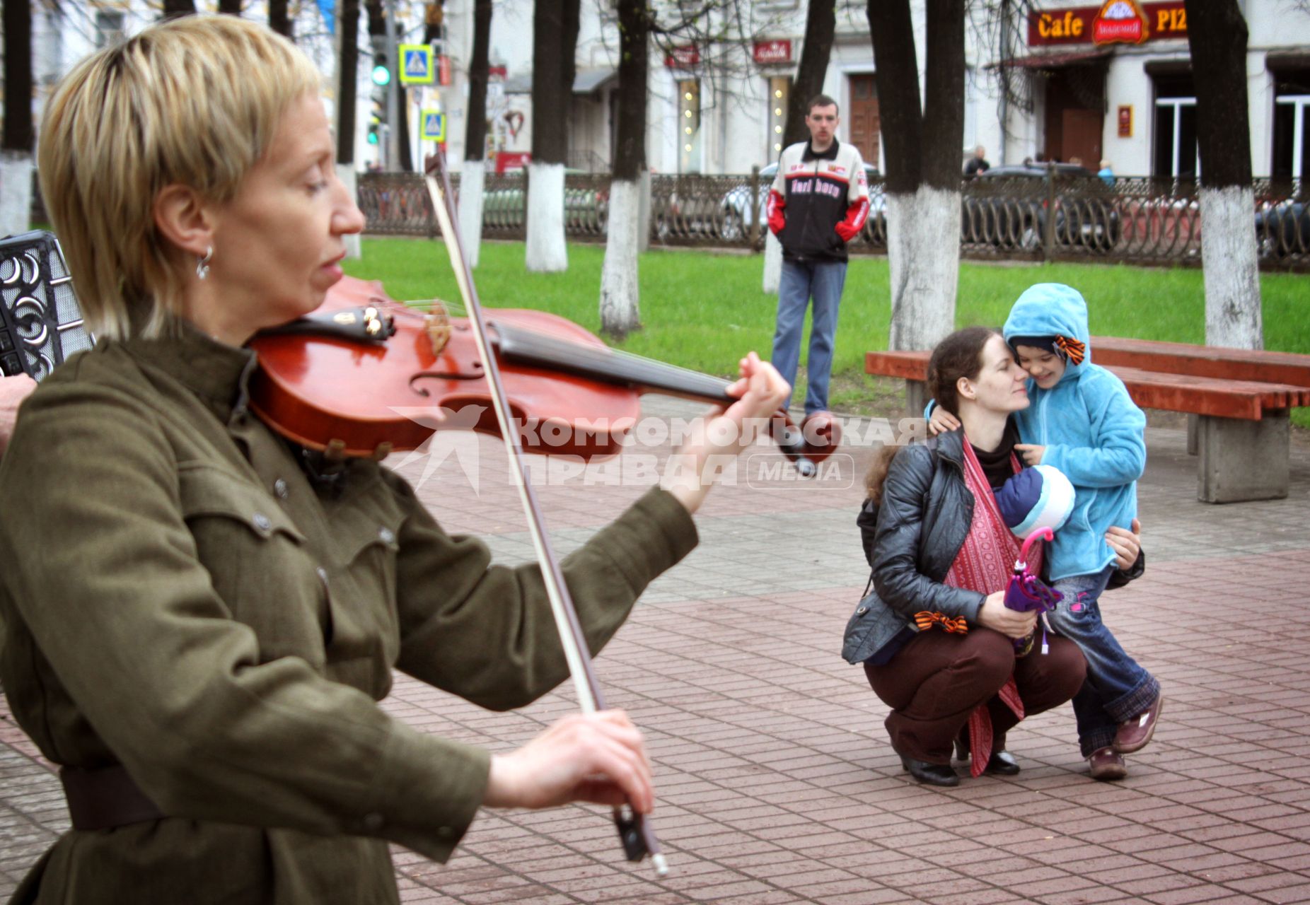 Женщина с ребенком слушают игру на скрипке.