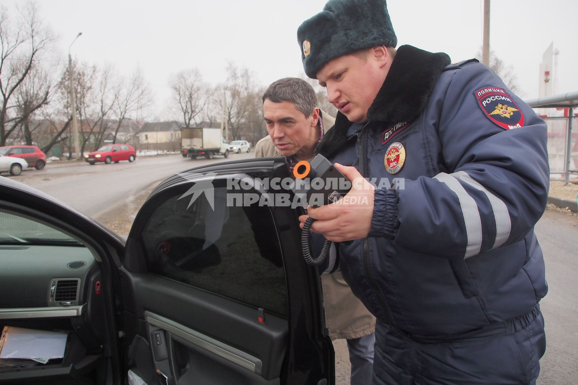 Сотрудник ДПС ГИБДД замеряет тонировку стекол автомобиля.