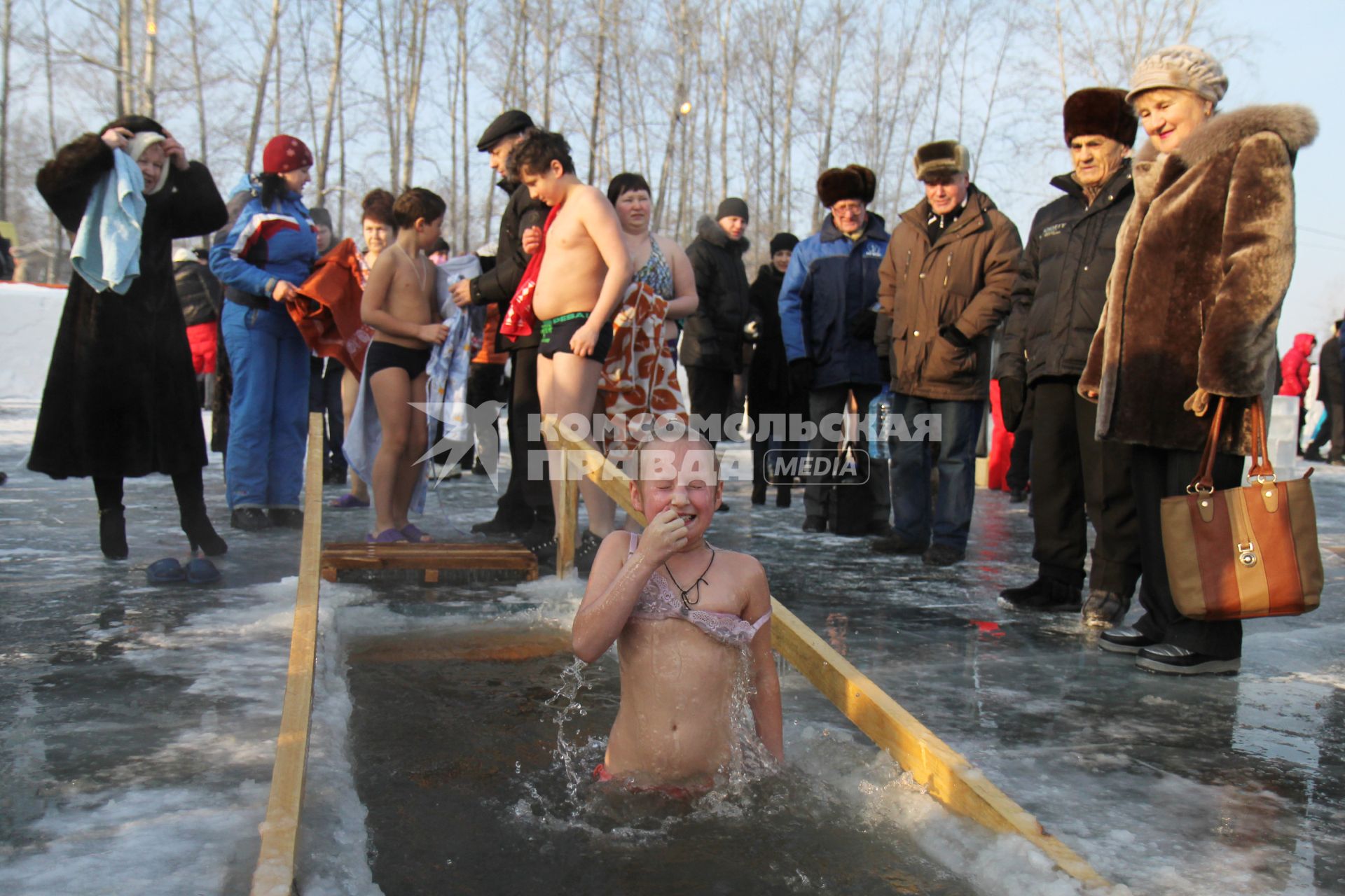 Ребенок окунается в проруби на крещение.