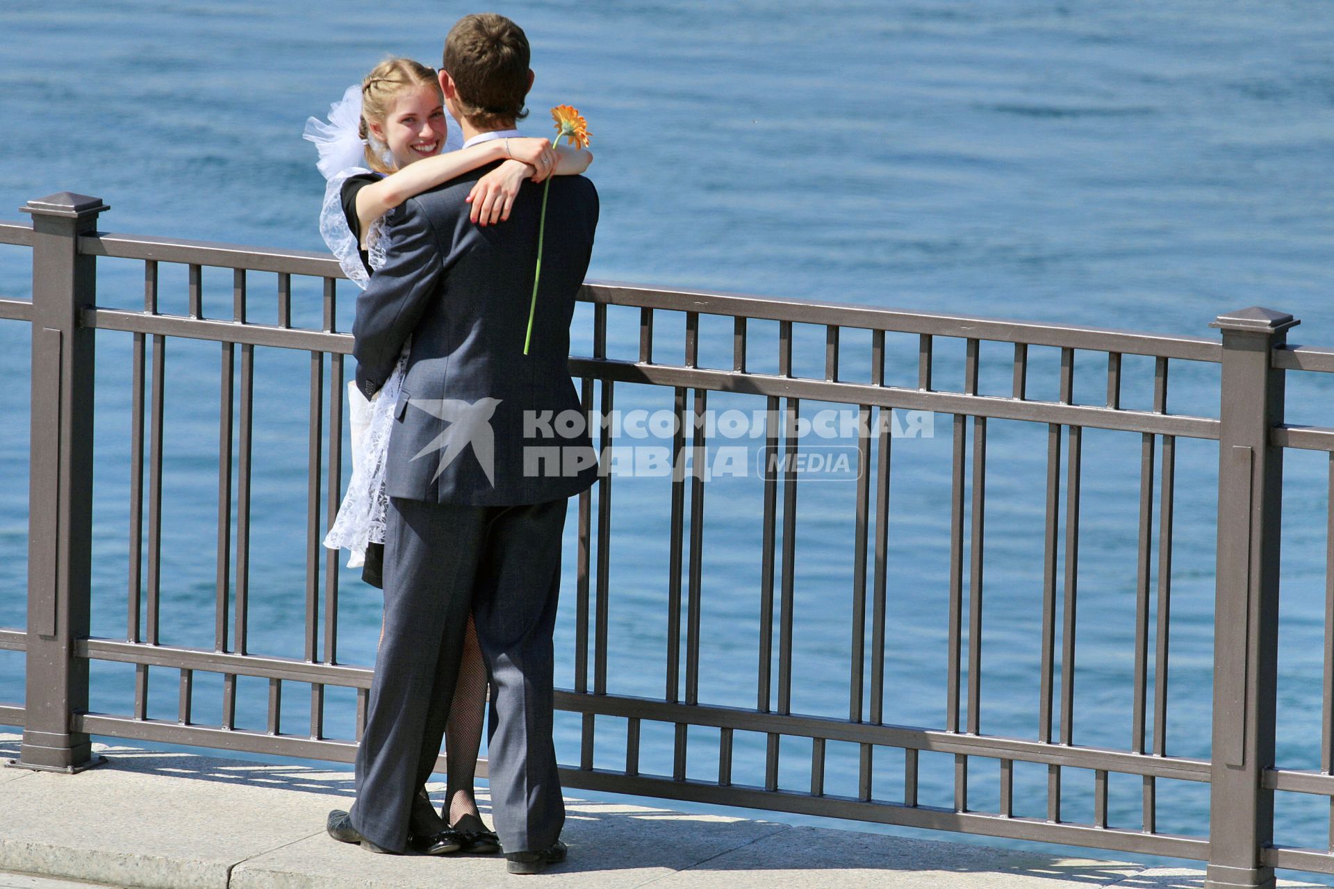 Последний звонок. Девушка обнимаются с юношей на набережной.