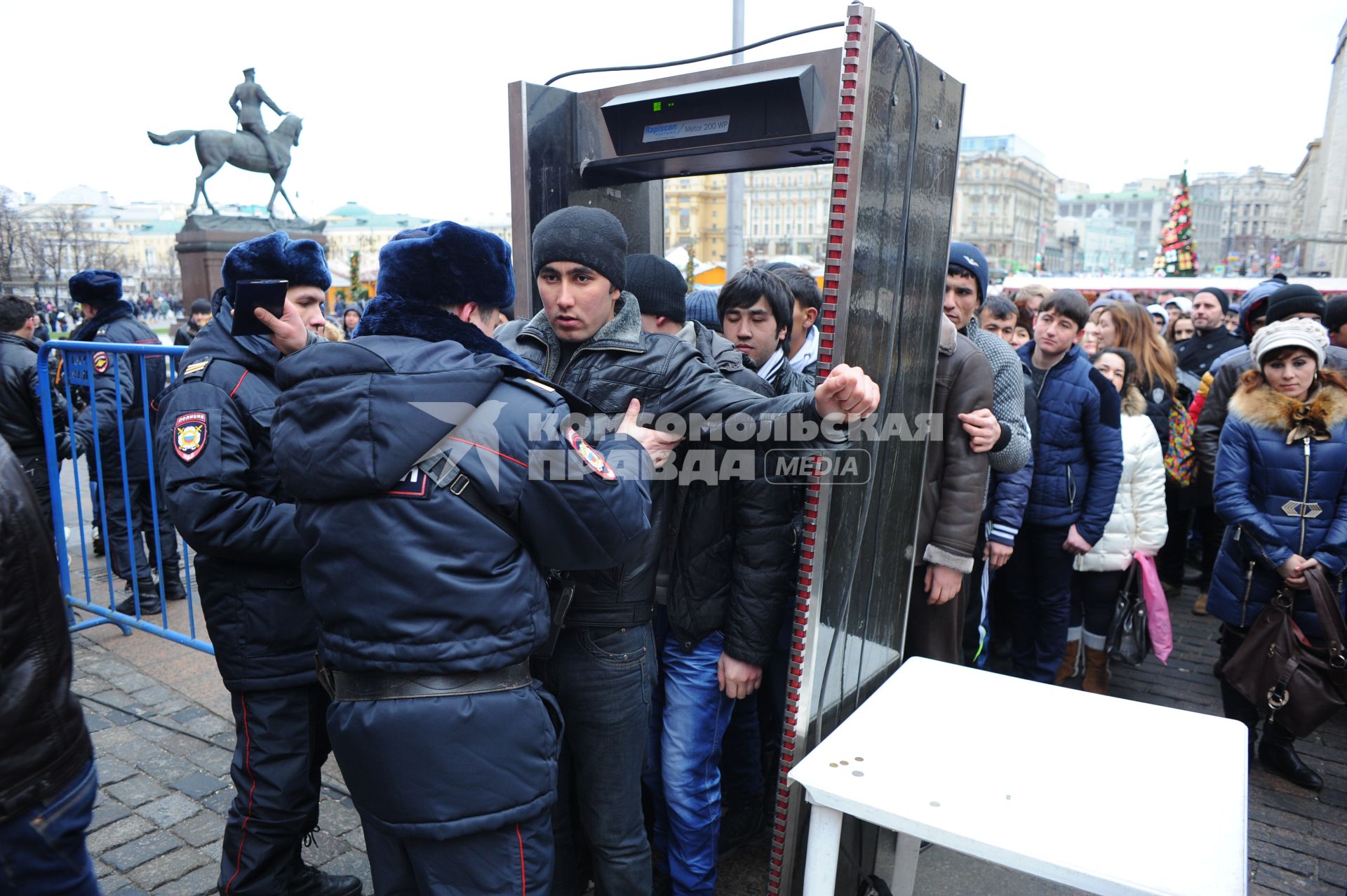 Мигранты из Средней Азии проходят на Красную Площадь через рамку металлоискатель.