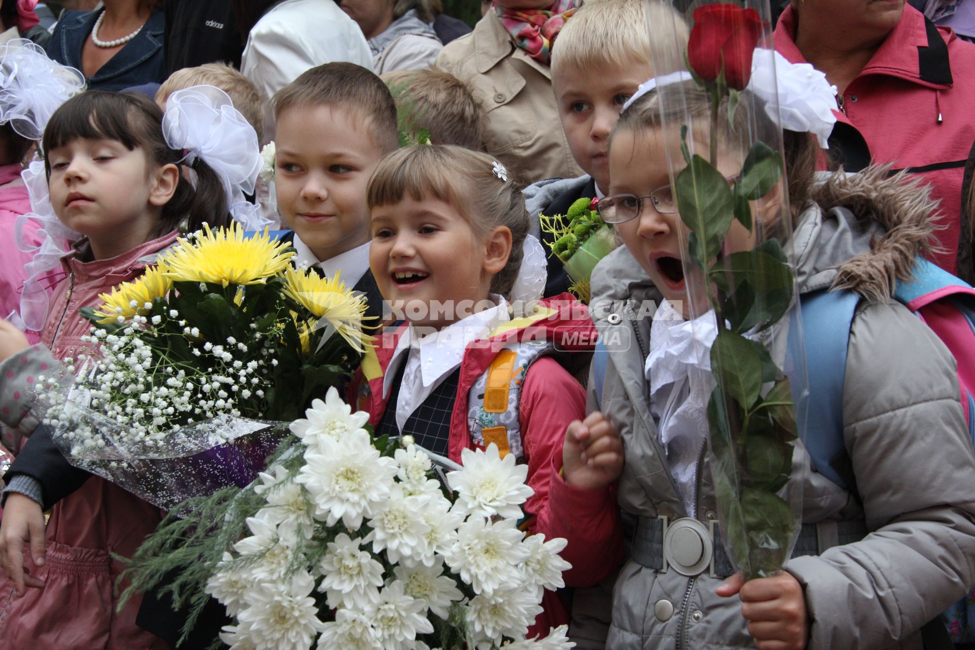 Первоклассники в день знаний на школьной линейке с букетами цветов..