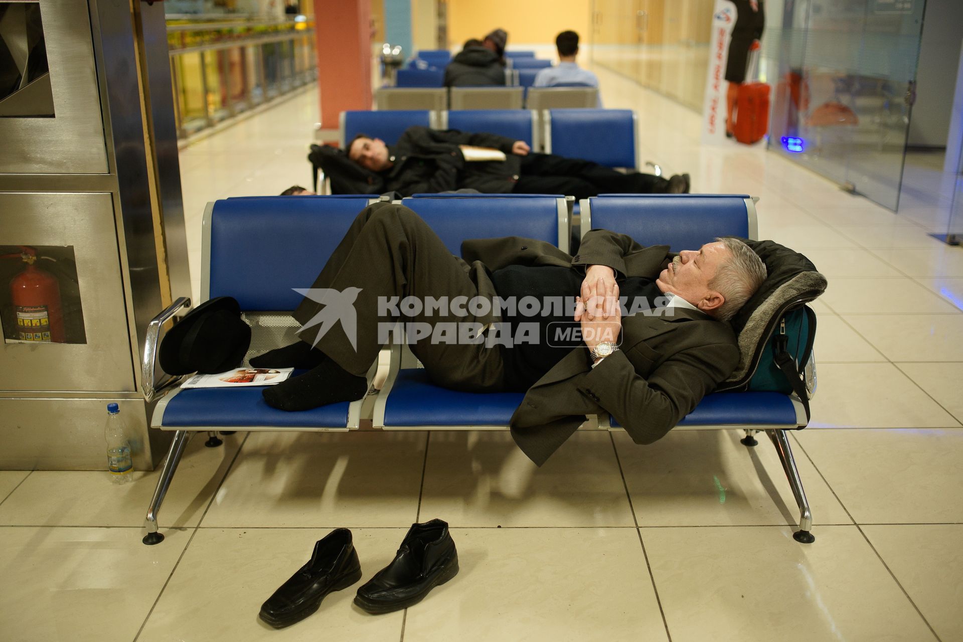 Мужчина спит на креслах в зале ожидания аэропорта.