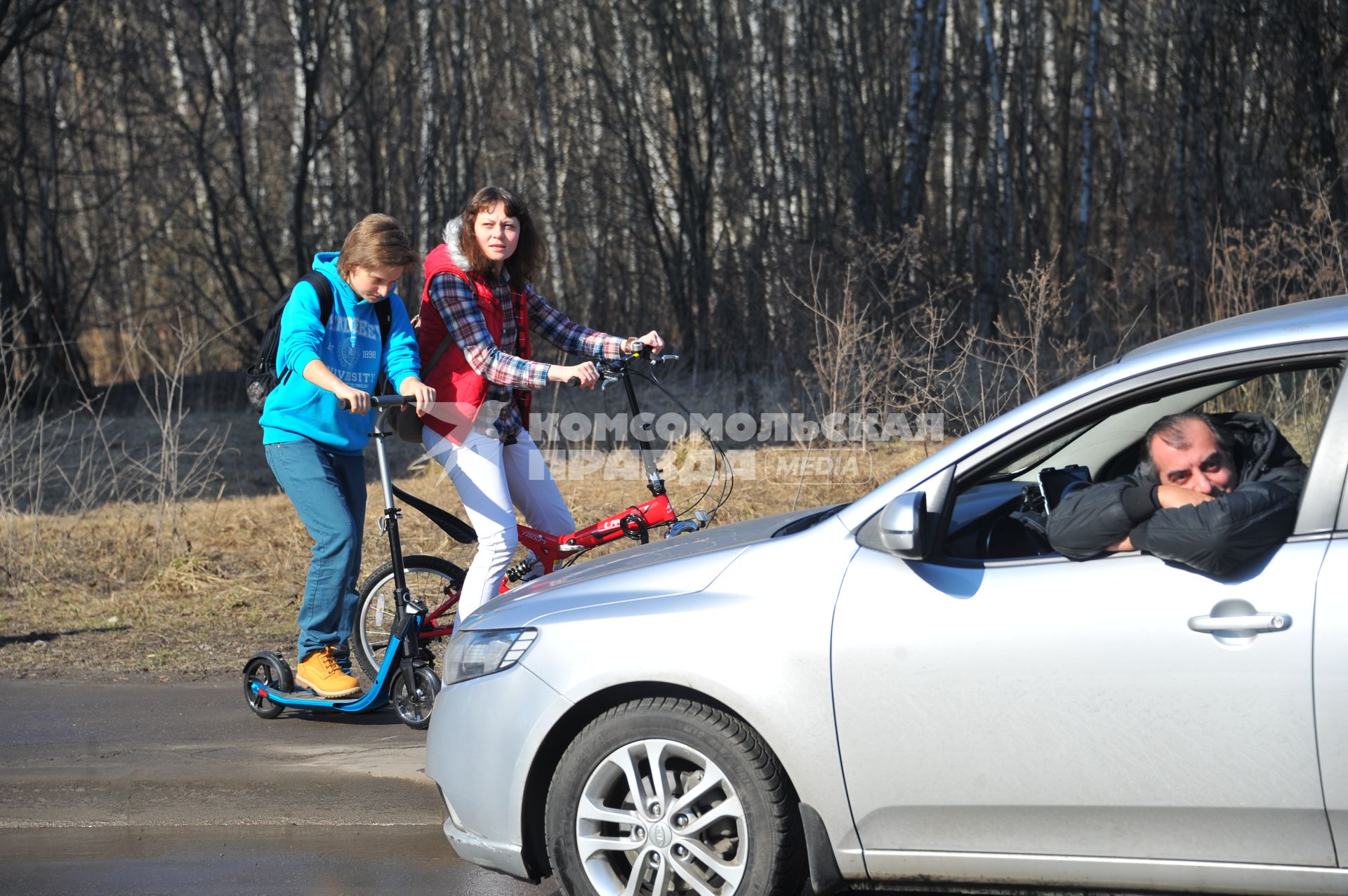 Температурный рекорд в Москве достиг 19 градусов. На снимке: девушки на самокате и велосипеде и водитель.