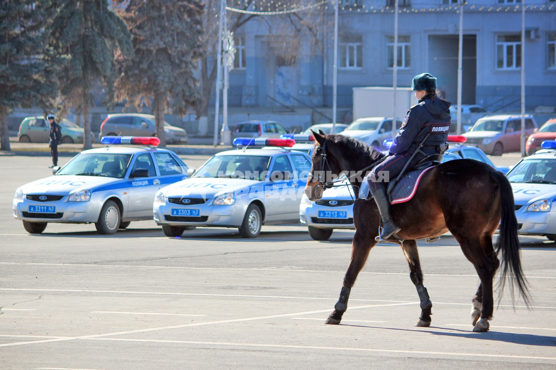 Женщина из конной полиции на фоне полицейских автомобилей.