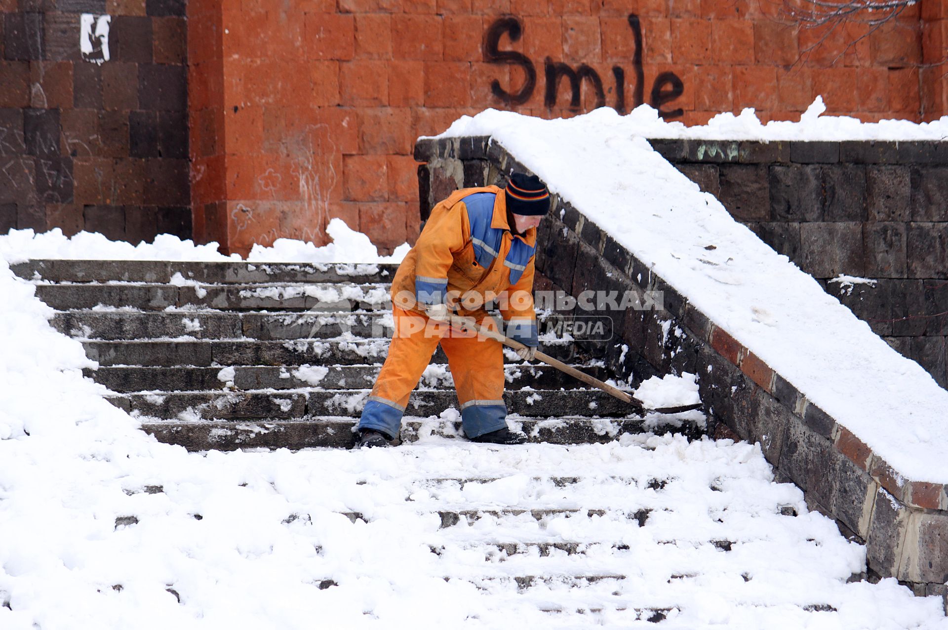 Дворник счищает снег с лестницы.