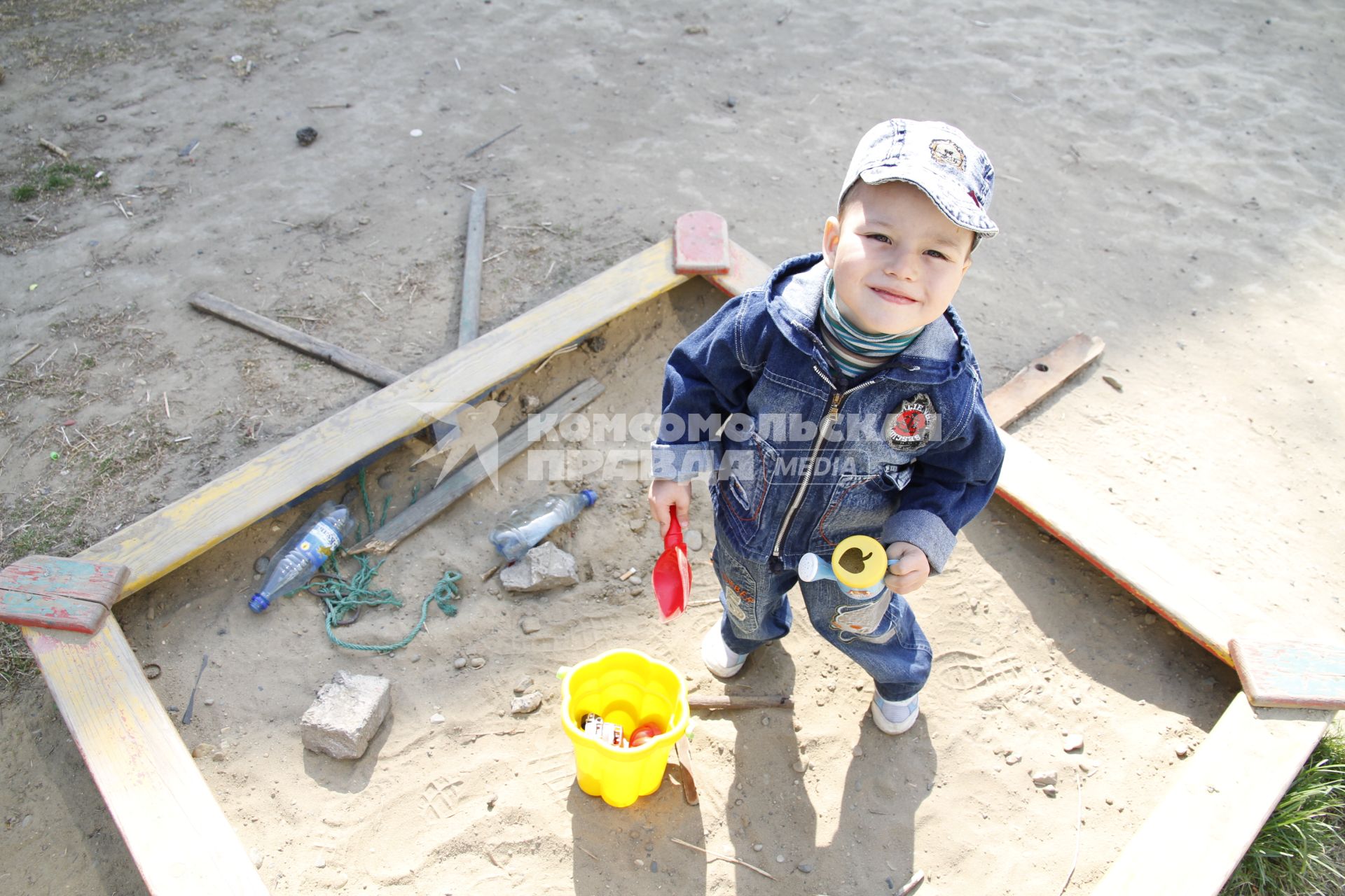 Ребенок на детской площадке играет в песочнице.