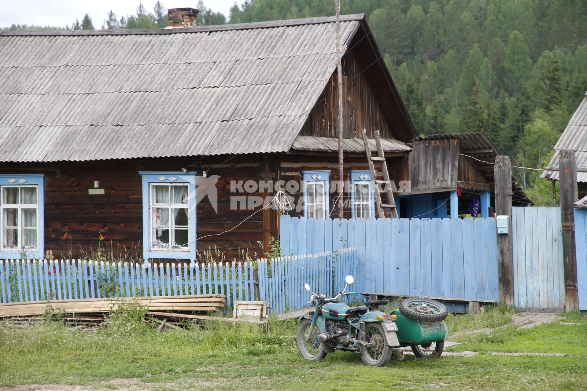 Деревенский дом, рядом стоит мотоцикл с коляской.
