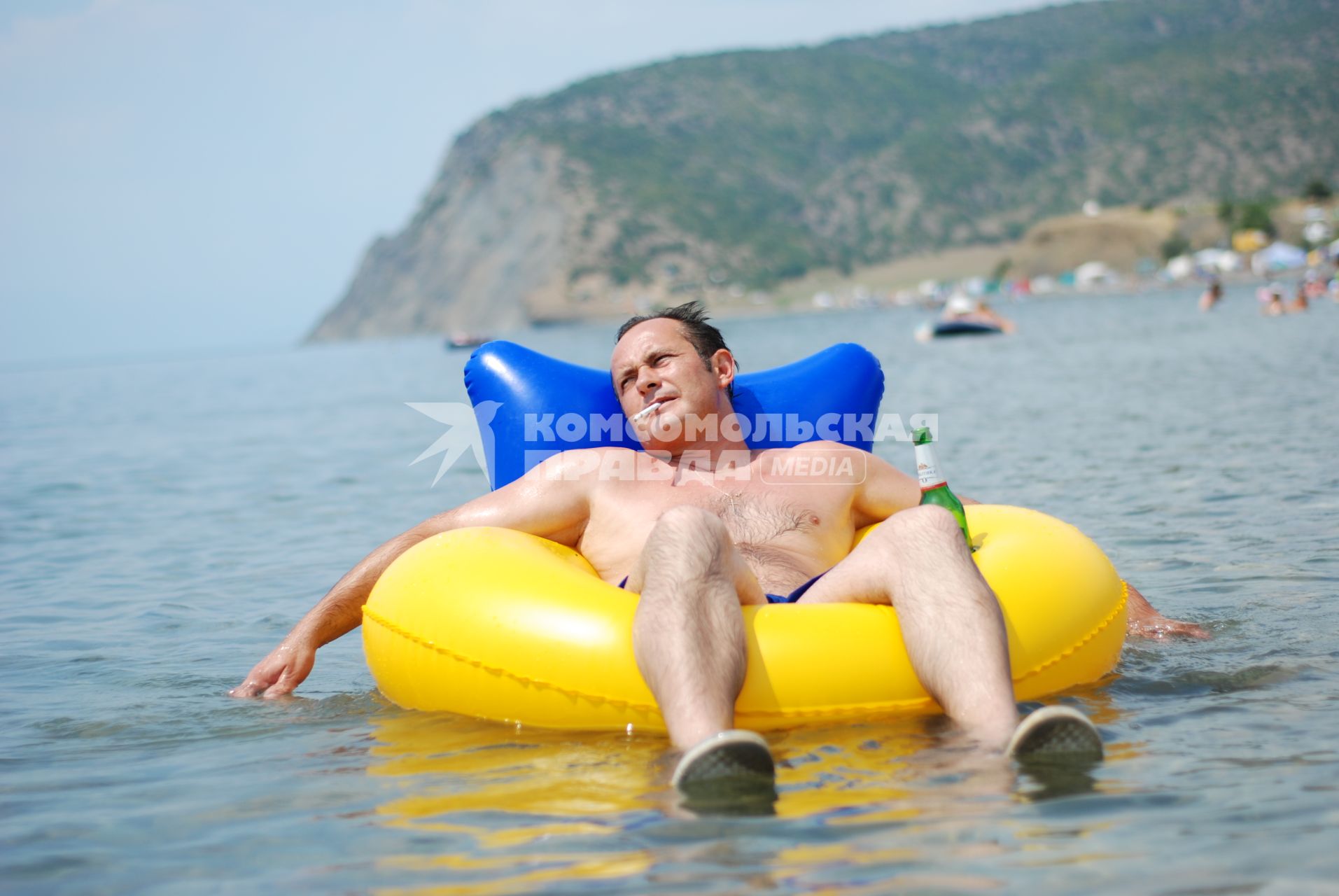 Отдых в Крыму. На снимке: мужчина с сигаретой и бутылкой пива отдыхает на надувной круге в море и ему хорошо.