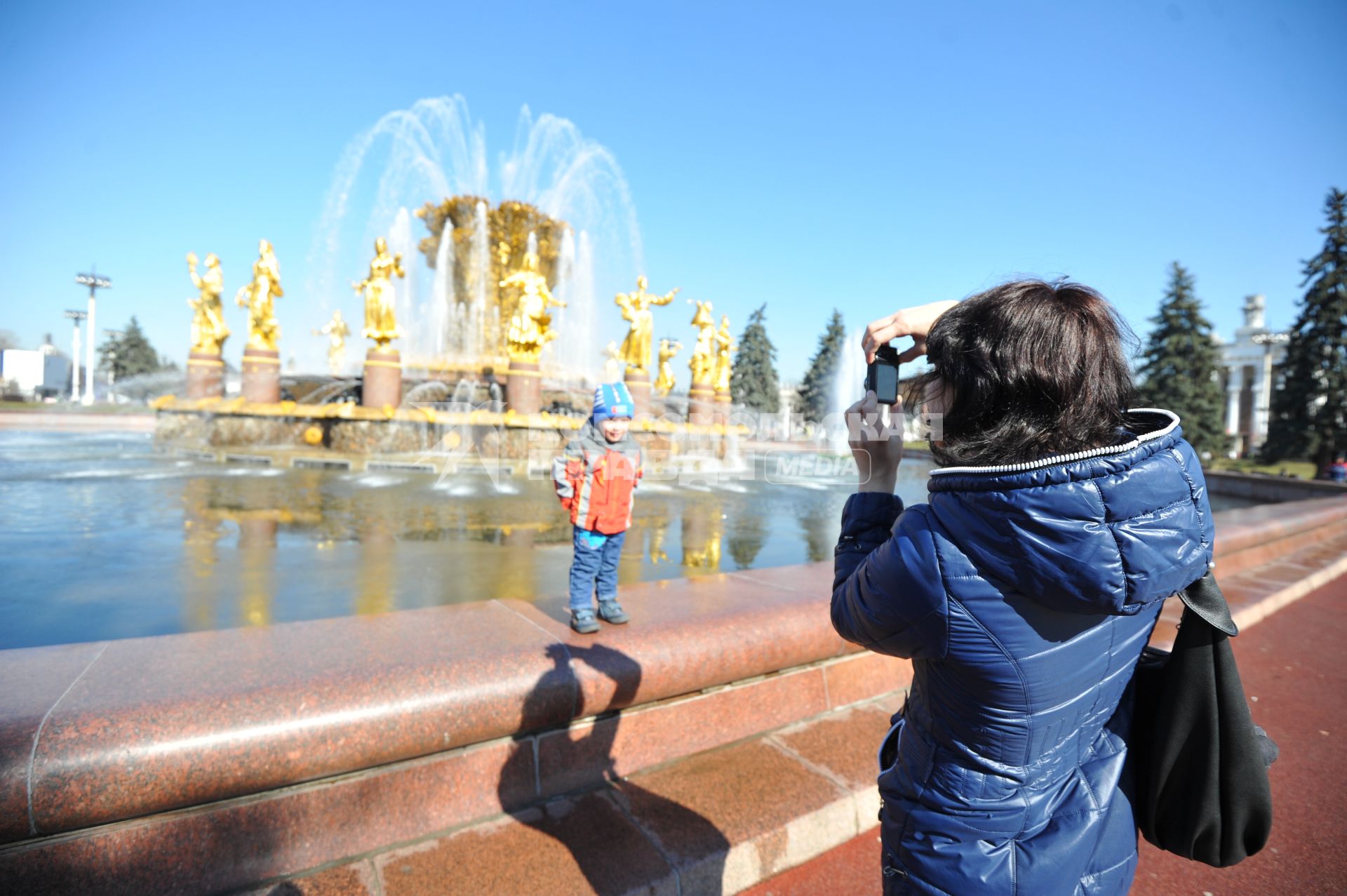 ВВЦ. На снимке: женщина фотографирует ребенка на фоне фонтана `Дружба народов`