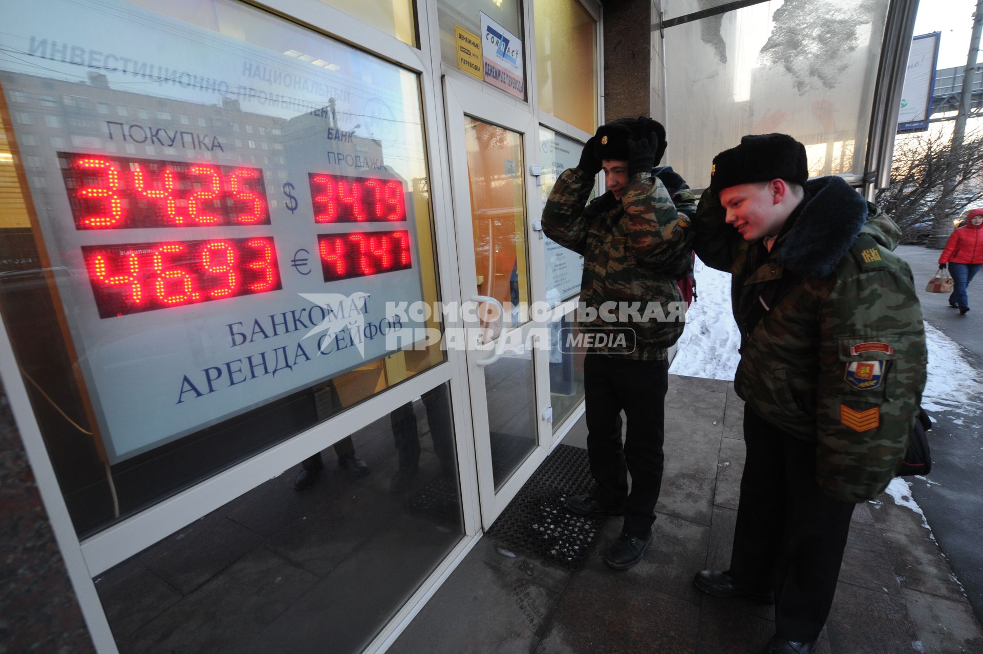 Пункт обмена валюты. На снимке: молодые люди смотрят на табло с курсом валюты.