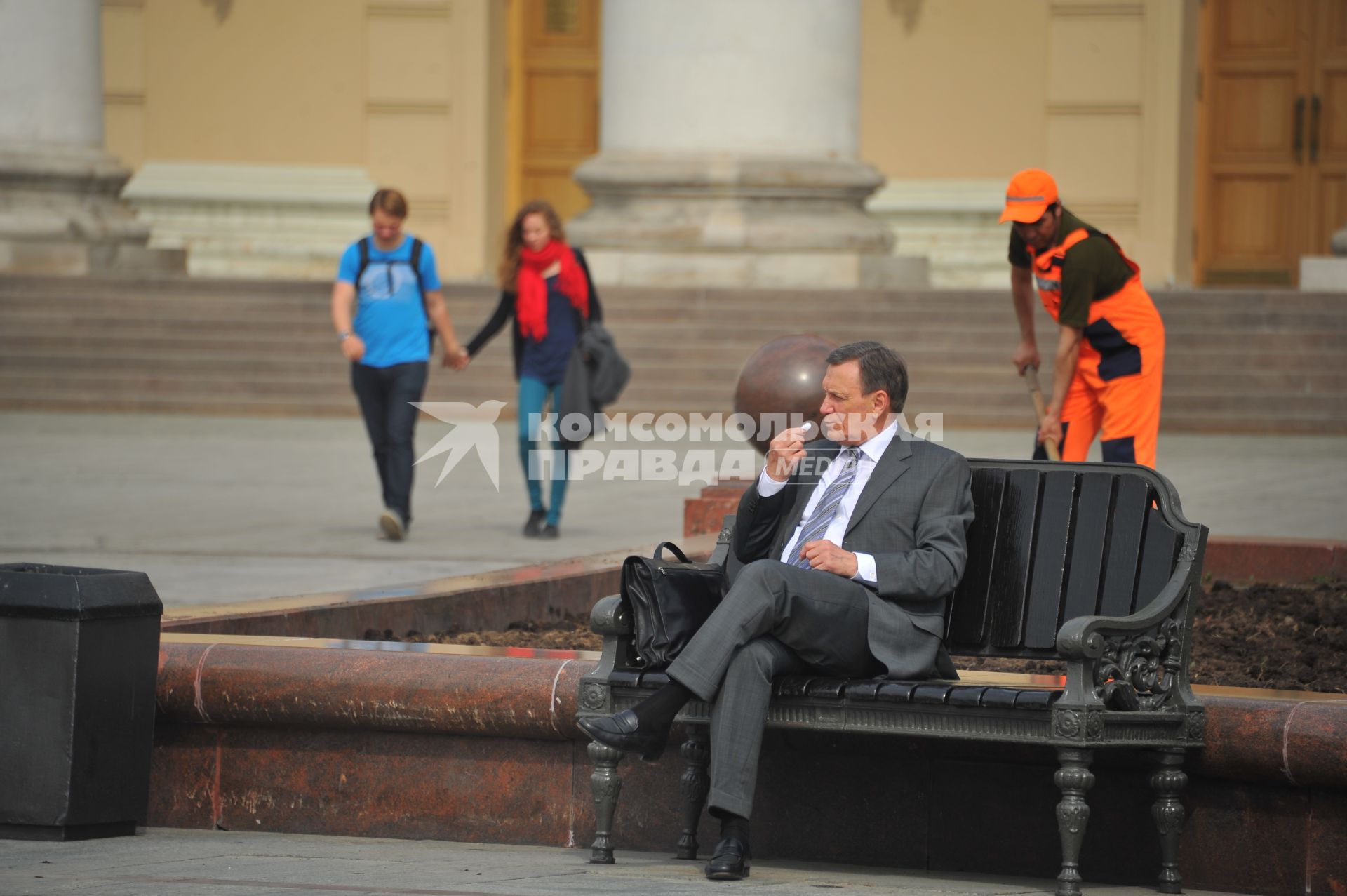 Мужчина в костюме и гастарбайтер перед зданием Большого театра.