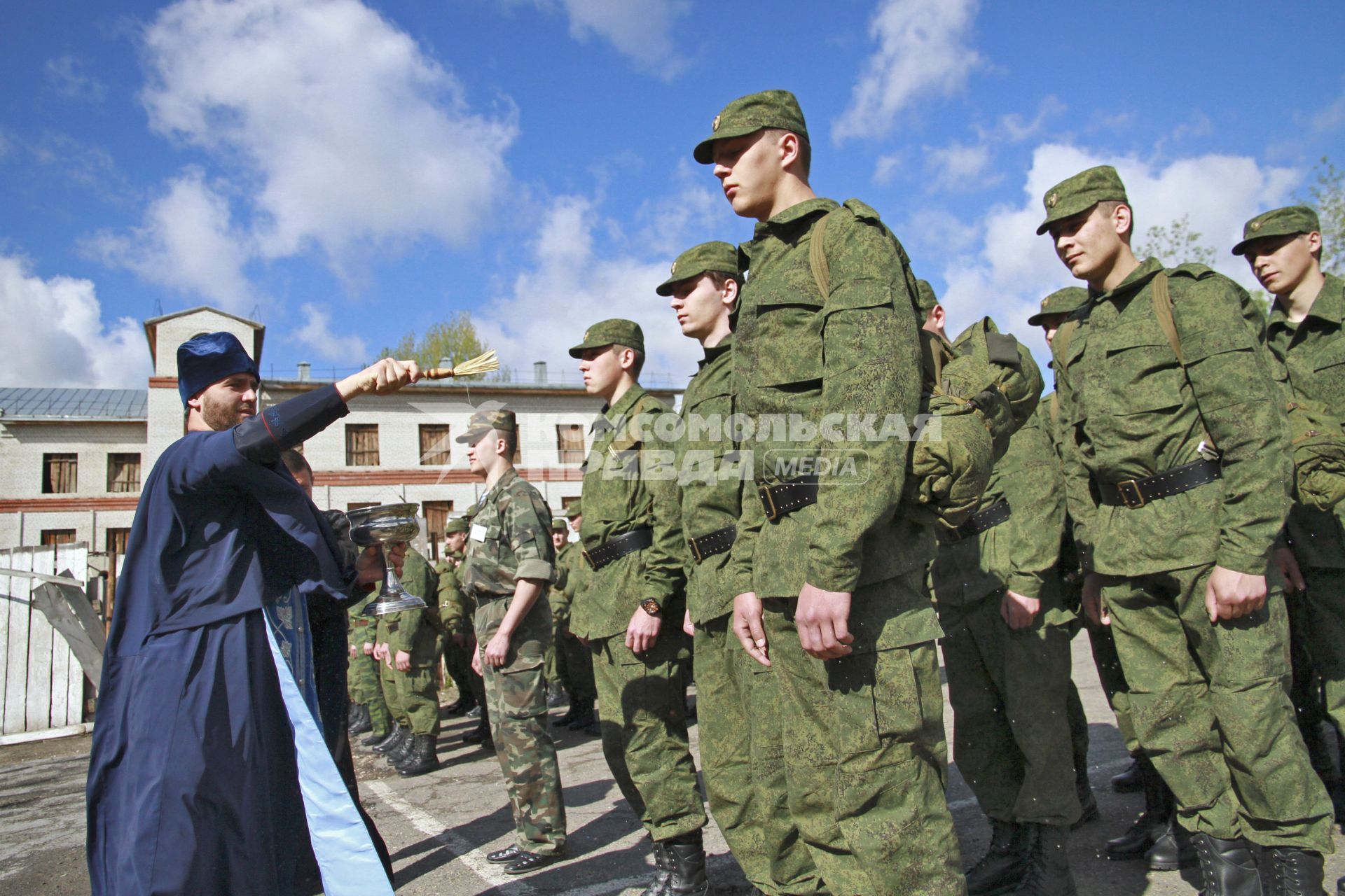 Новобранцы около призывного пункта. Священник окропляет новобранцев.