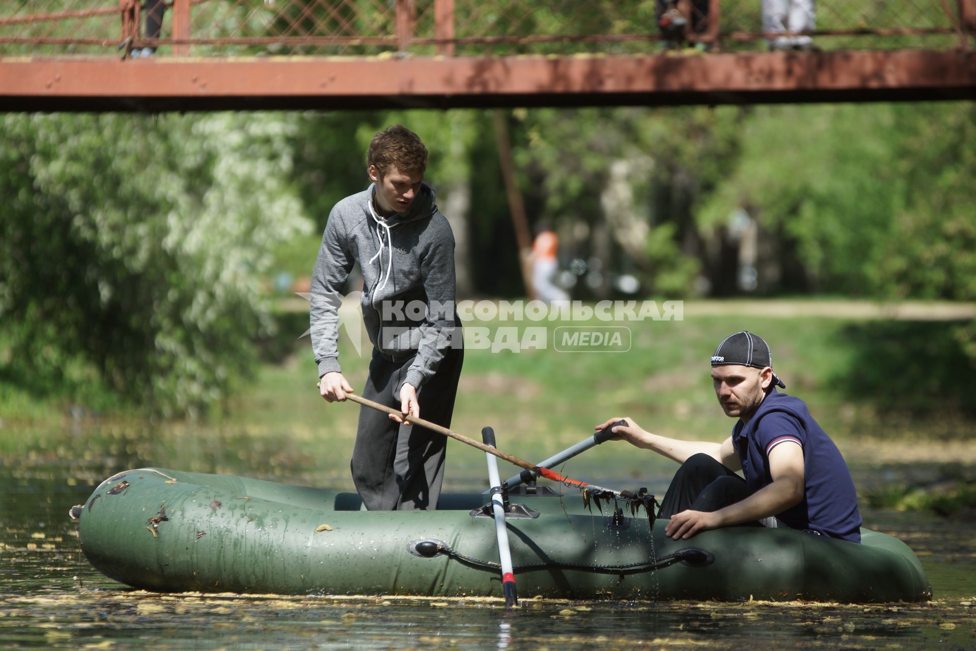 парень стоя в резиновой надувной лодке чистит городской пруд на субботнике в Харитоновском саду в Екатеринбурге
