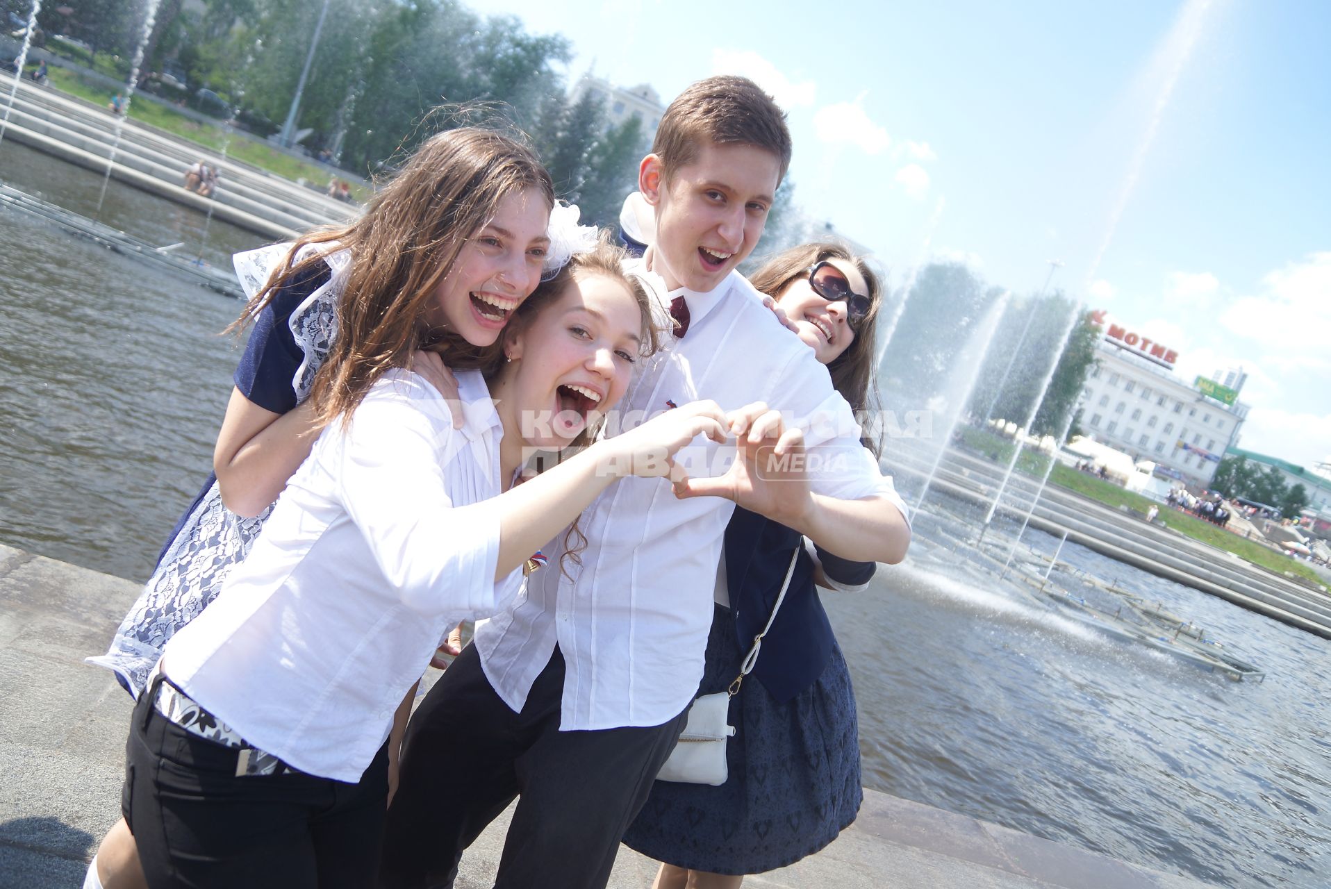 Выпускники фотографируются на набрежной у фонтана во время празднования последнего звонка в школах