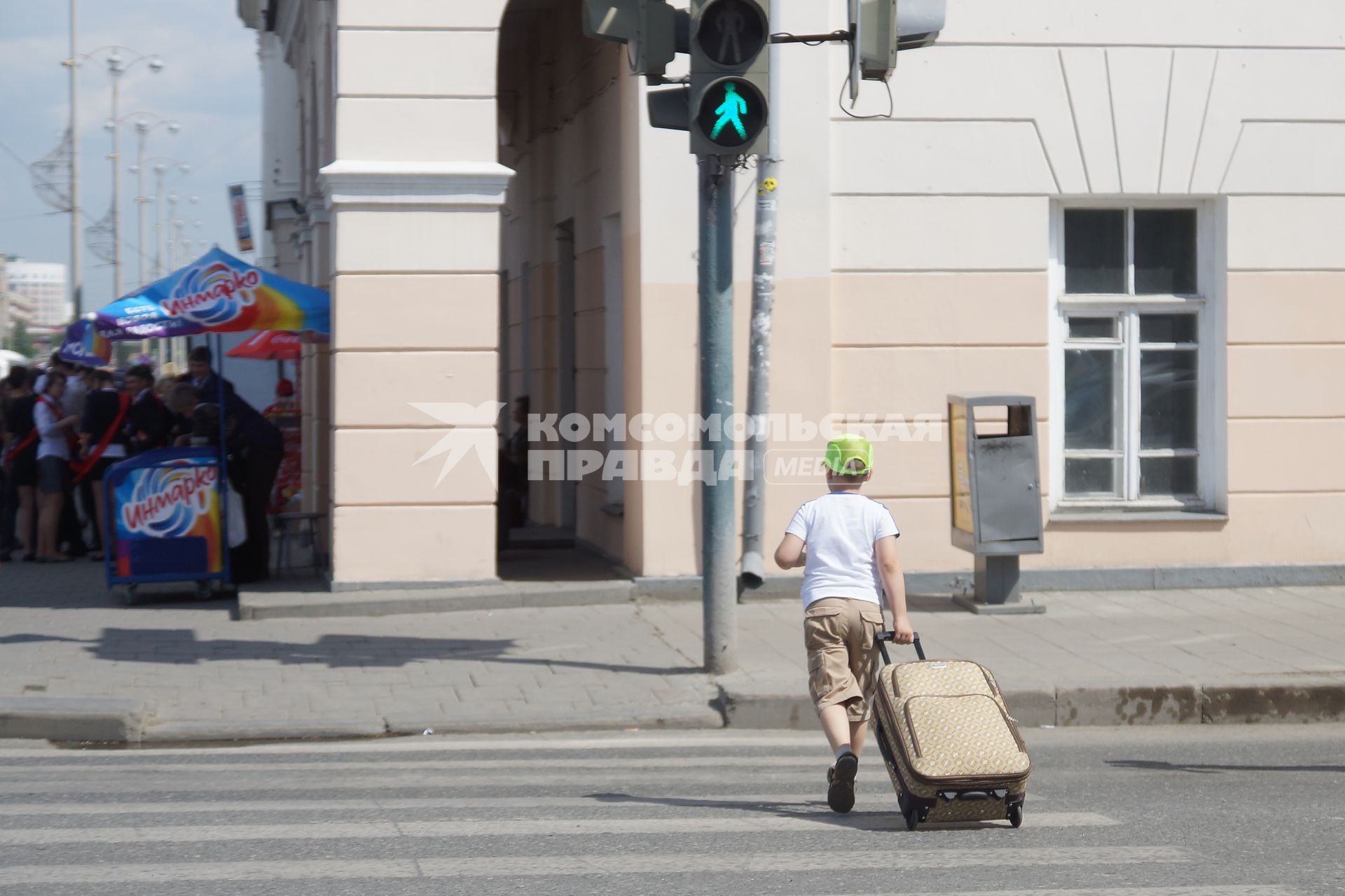 Мальчик везет чемодан через пешеходный переходу