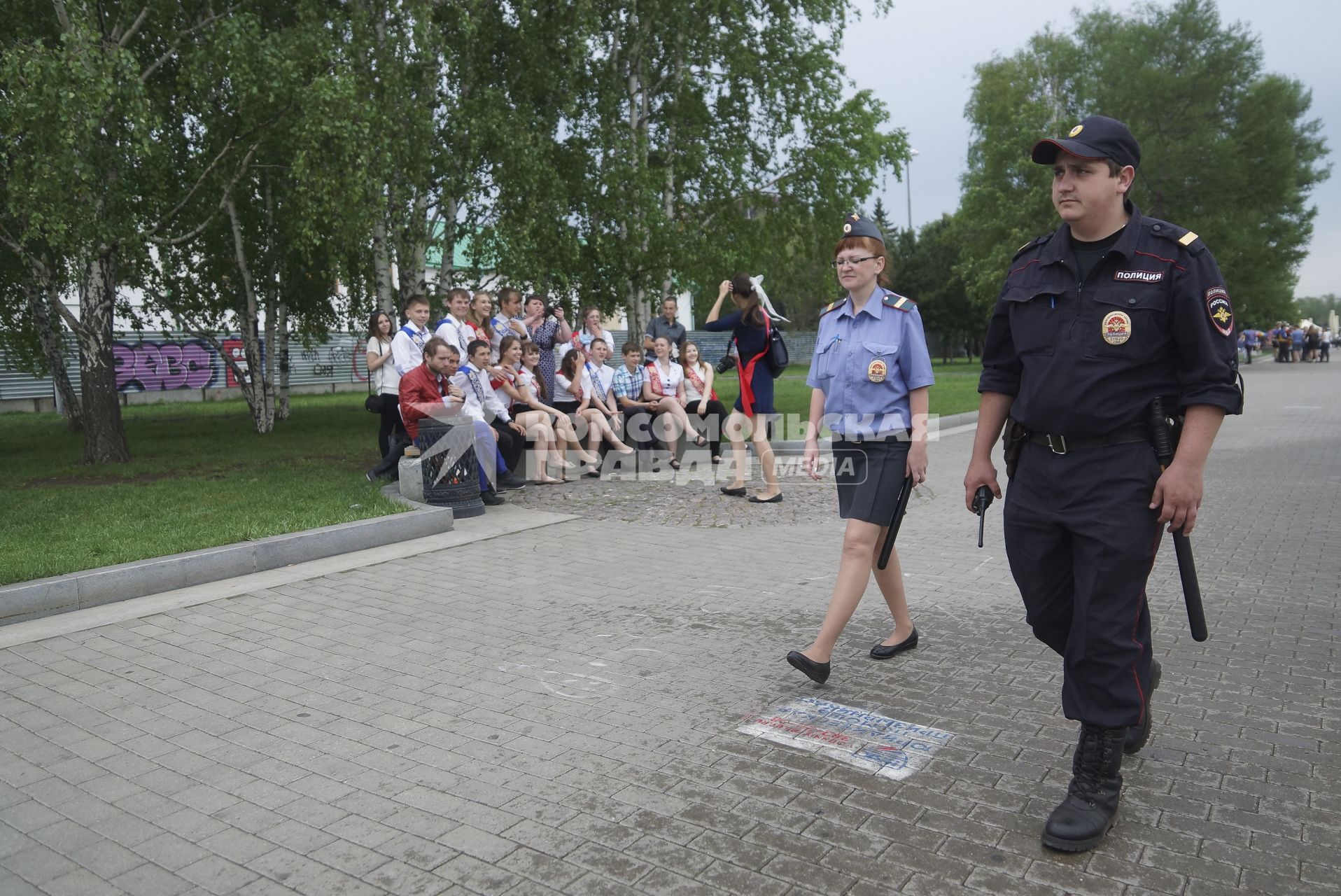 Полицейские проходят мимо группы выпускников в день последнего звонка