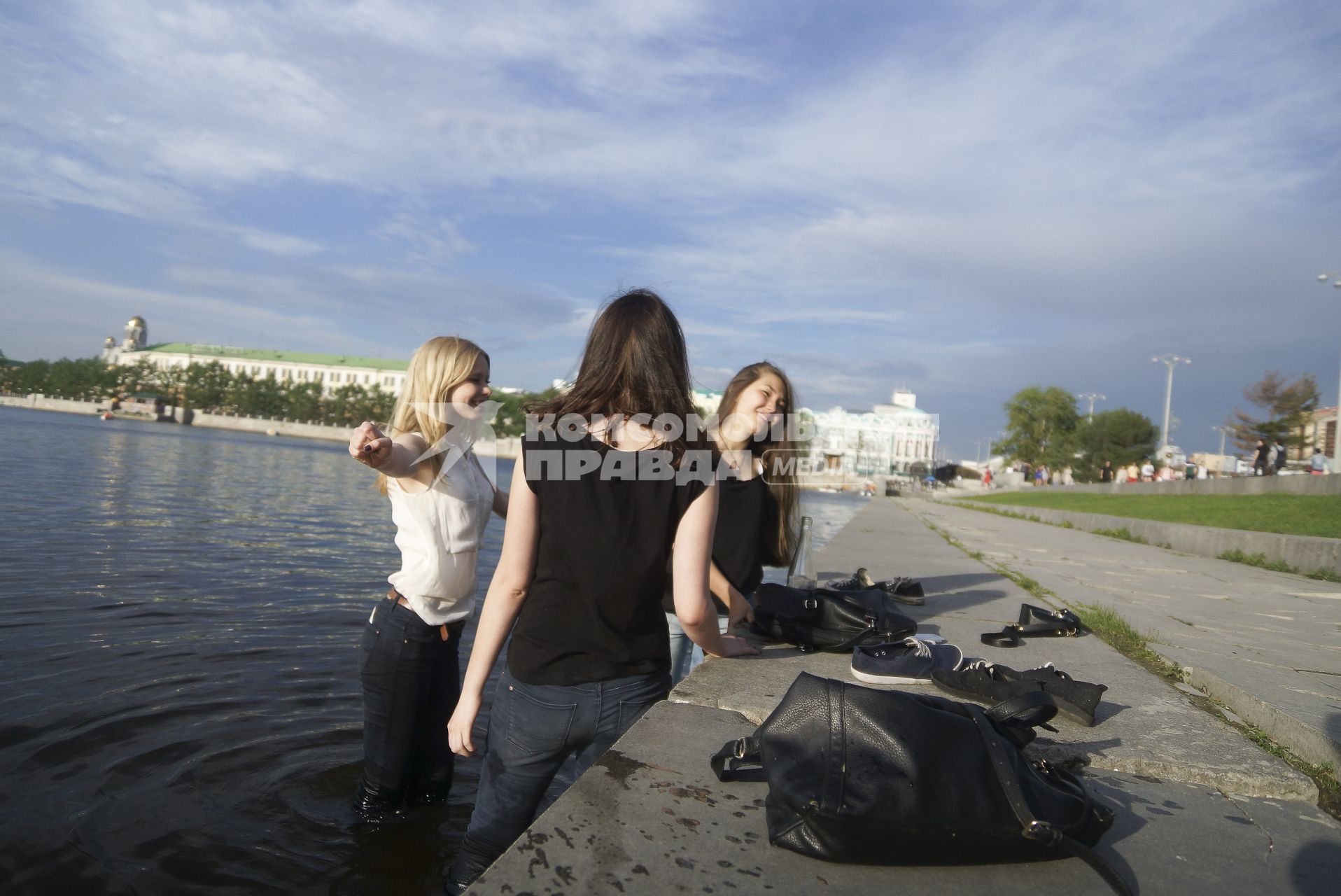 три девушки стоят в воде около набережной