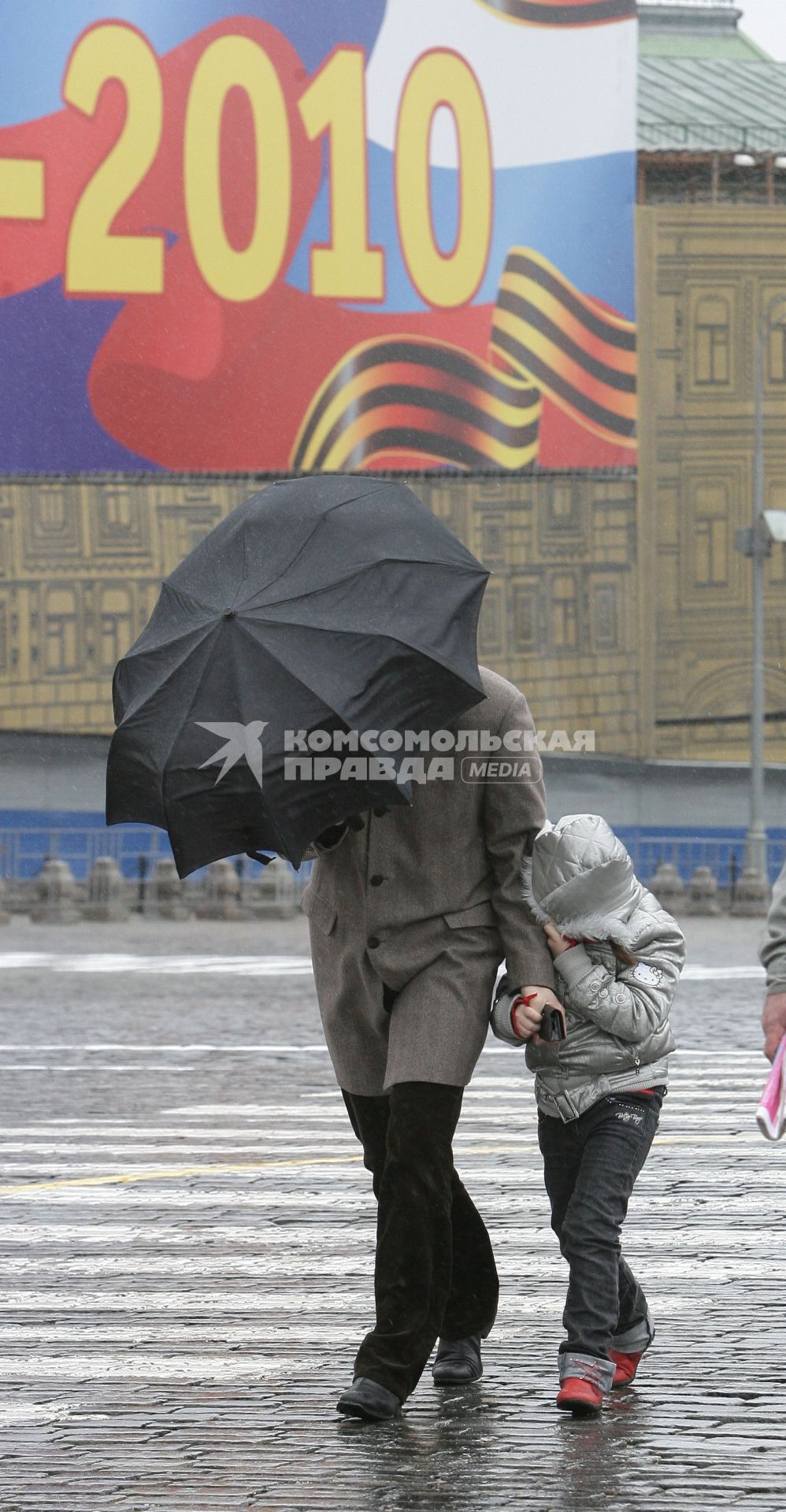 Папа с ребенком идут под зонтом.