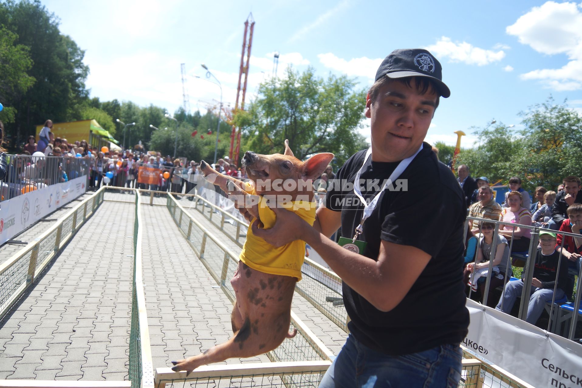 Мужчина несет поросенка перед забегом