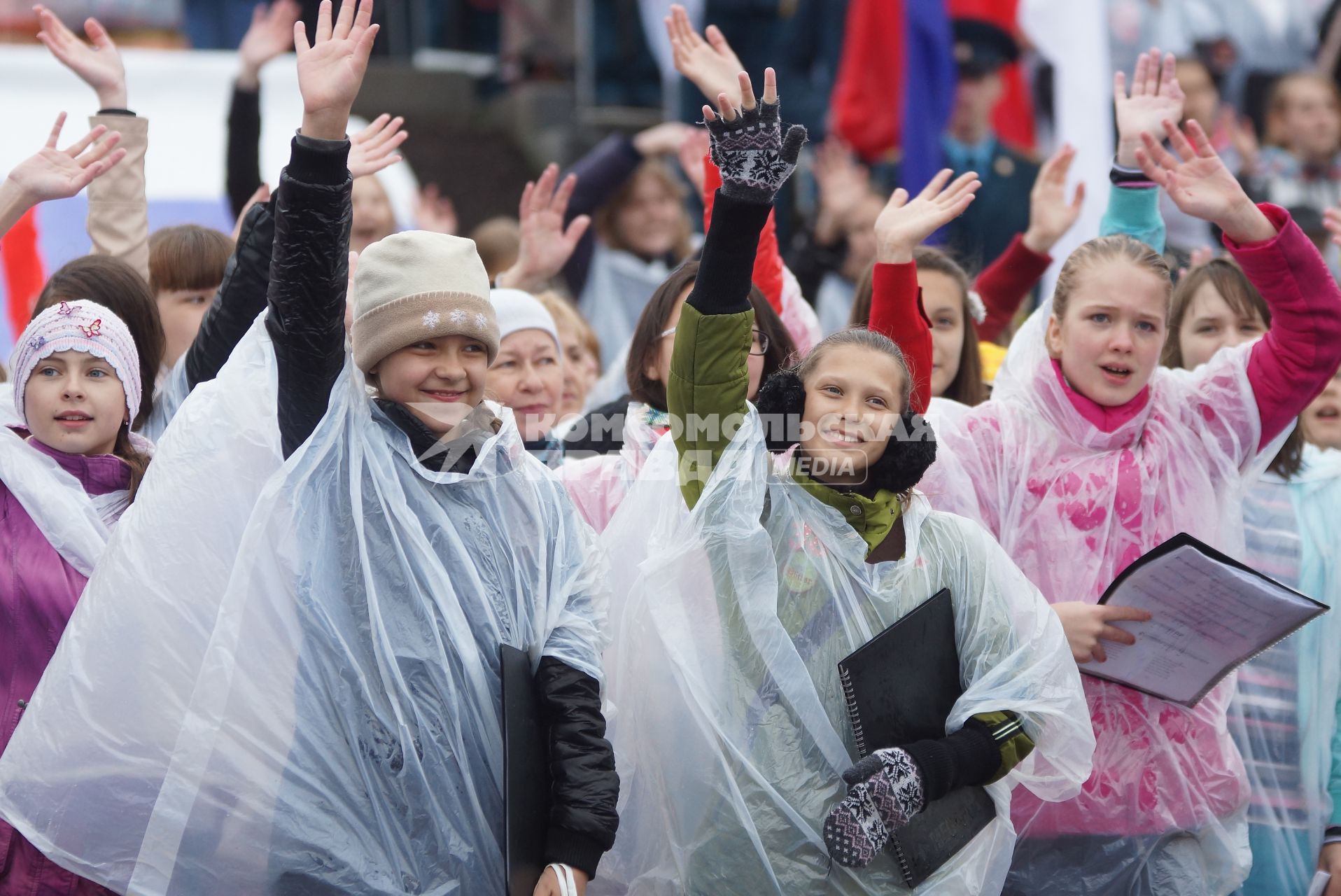 Дети в дождевиках во время выступления сводного хора из 1000 человек поют песни под дождем во время празднования дня России