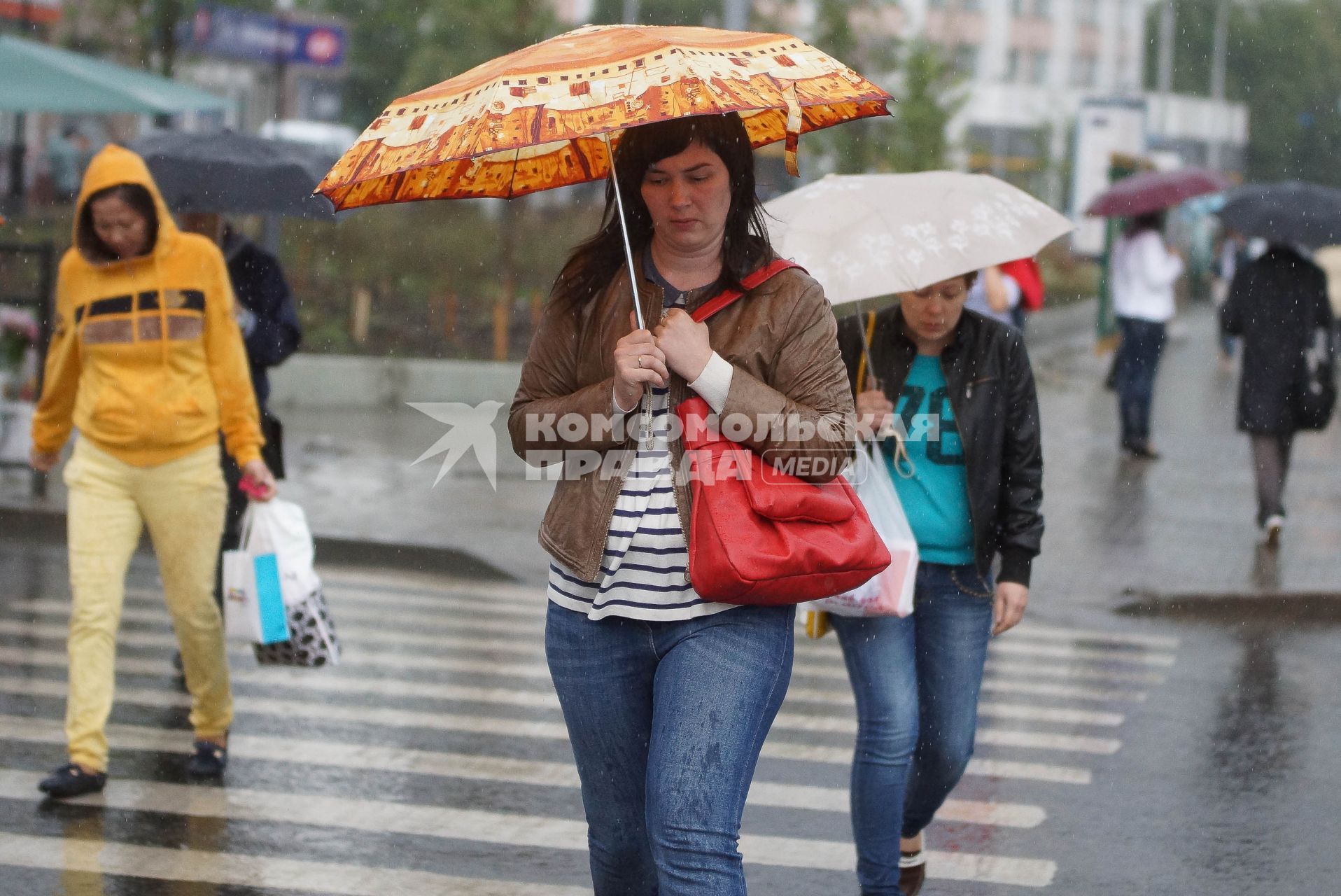 женщина под зонтом переходит дорогу во время дождя