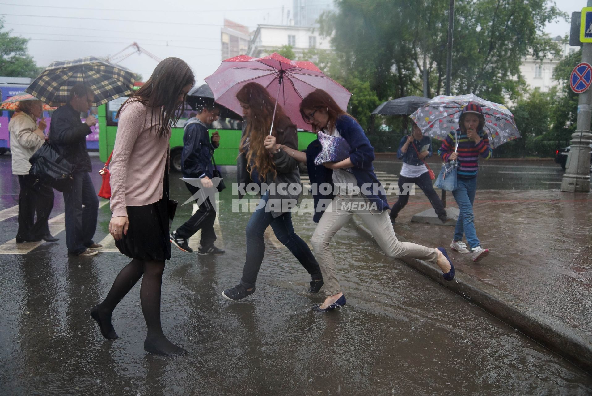 Девушки перепрыгивают широкие лужи во время дождя