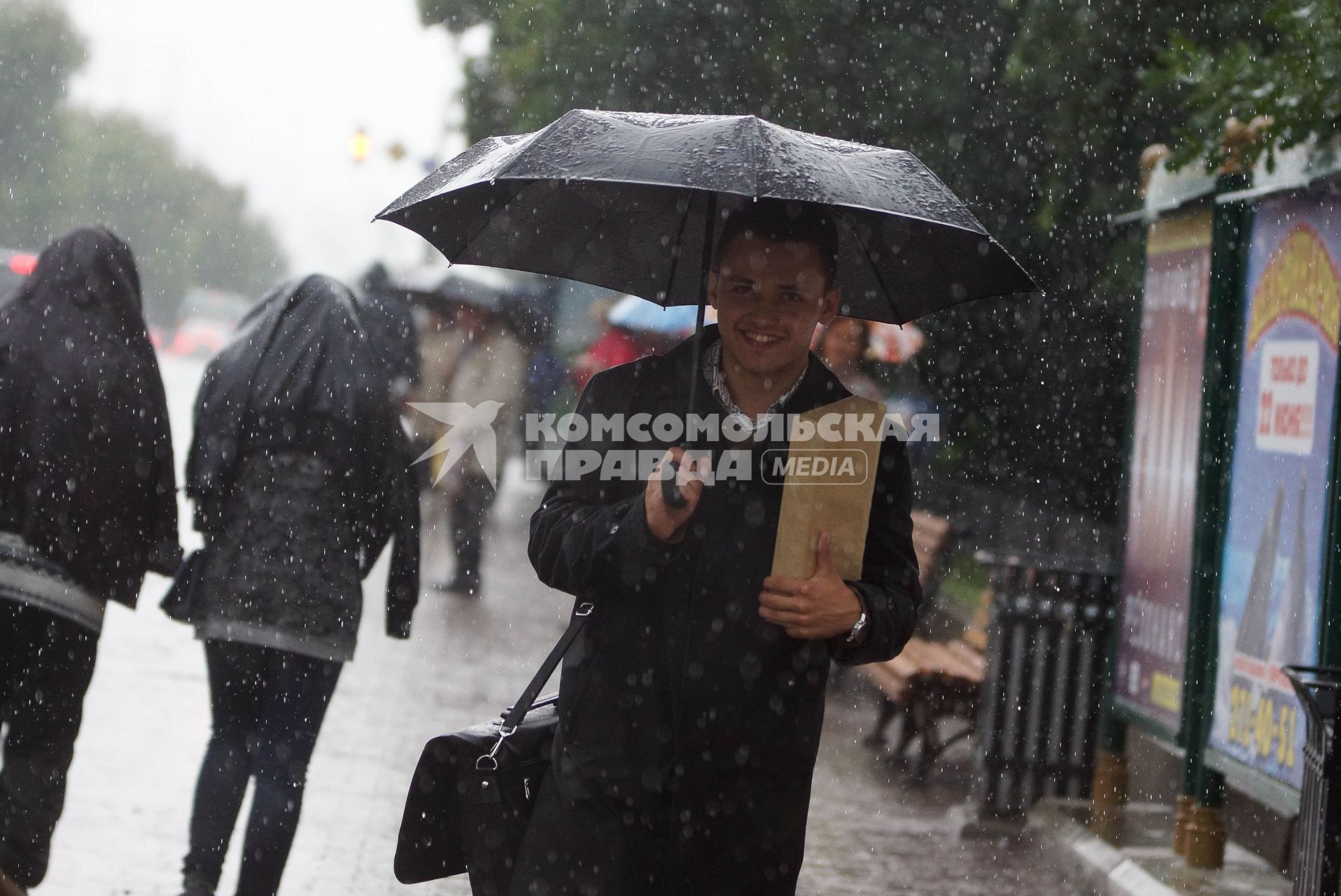 парень под зонтом улыбается во время дождя