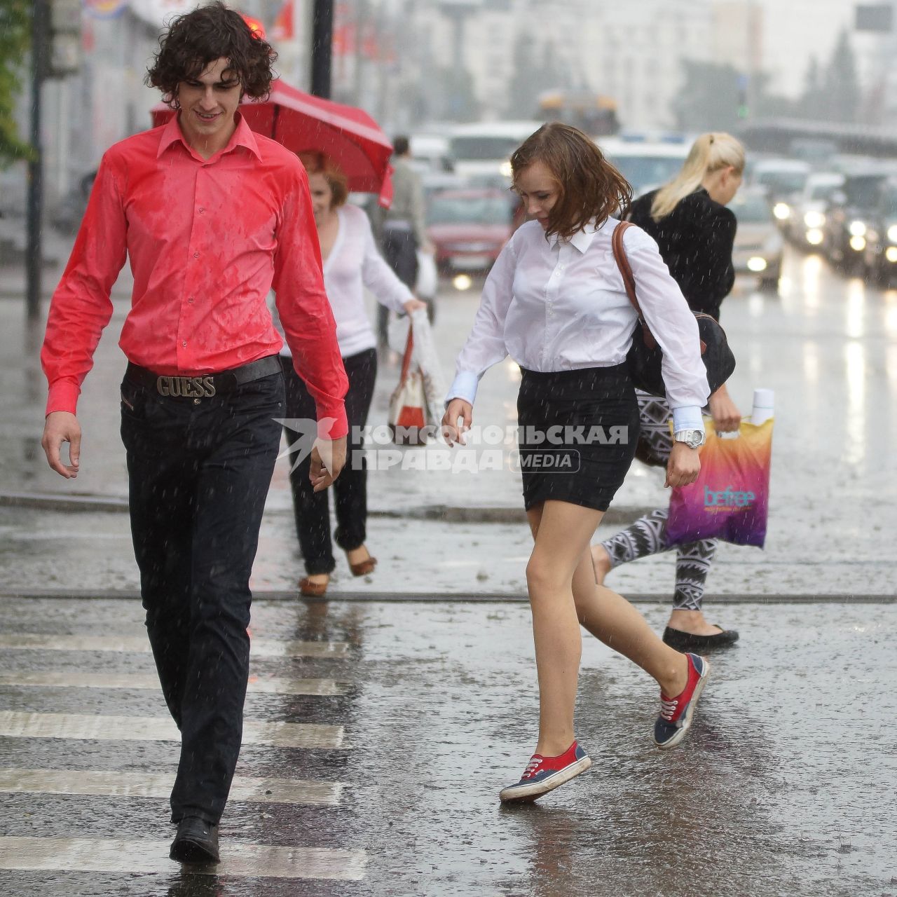 Девушка и парень переходят дорогу во время дождя