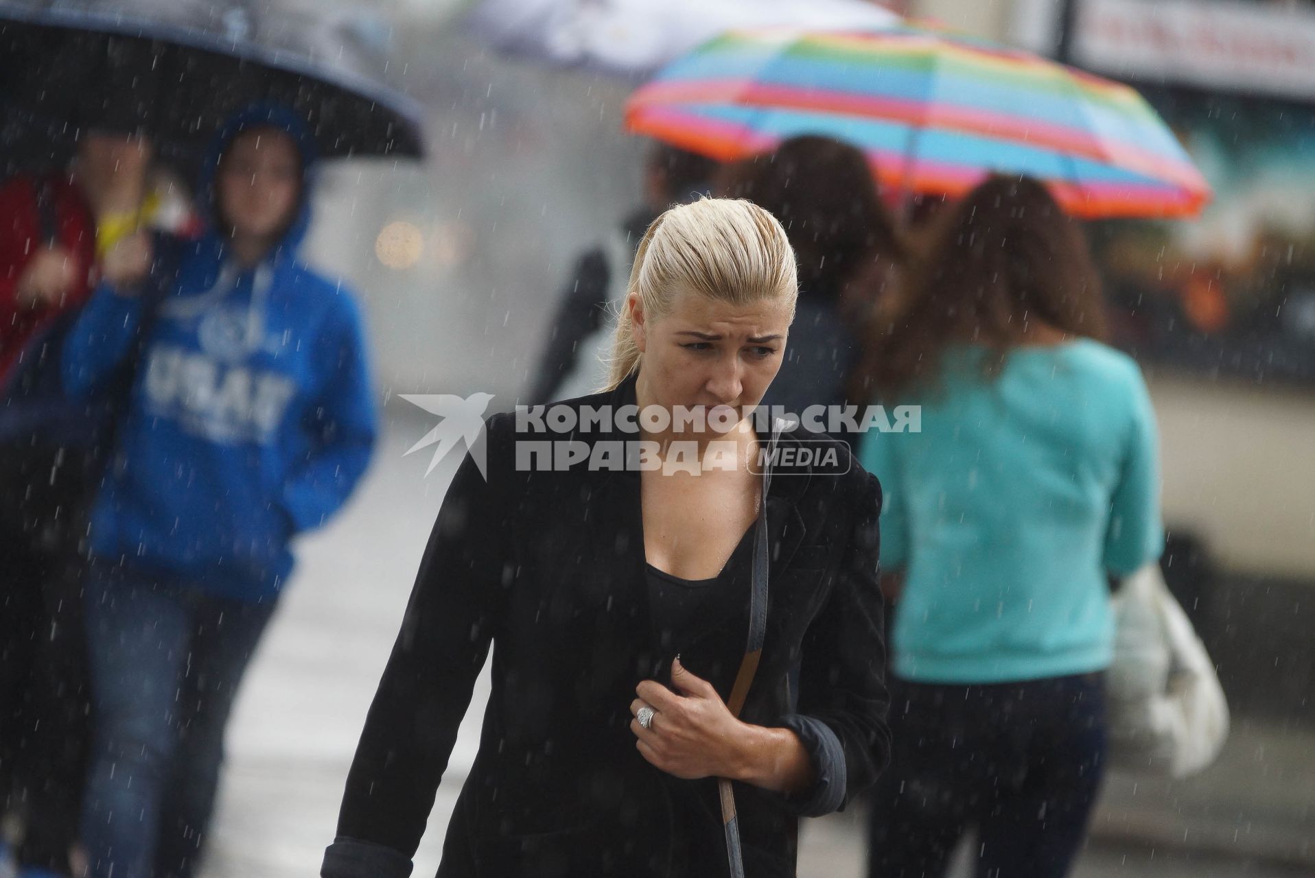 Девушка и пешеходы переходят дорогу во время дождя