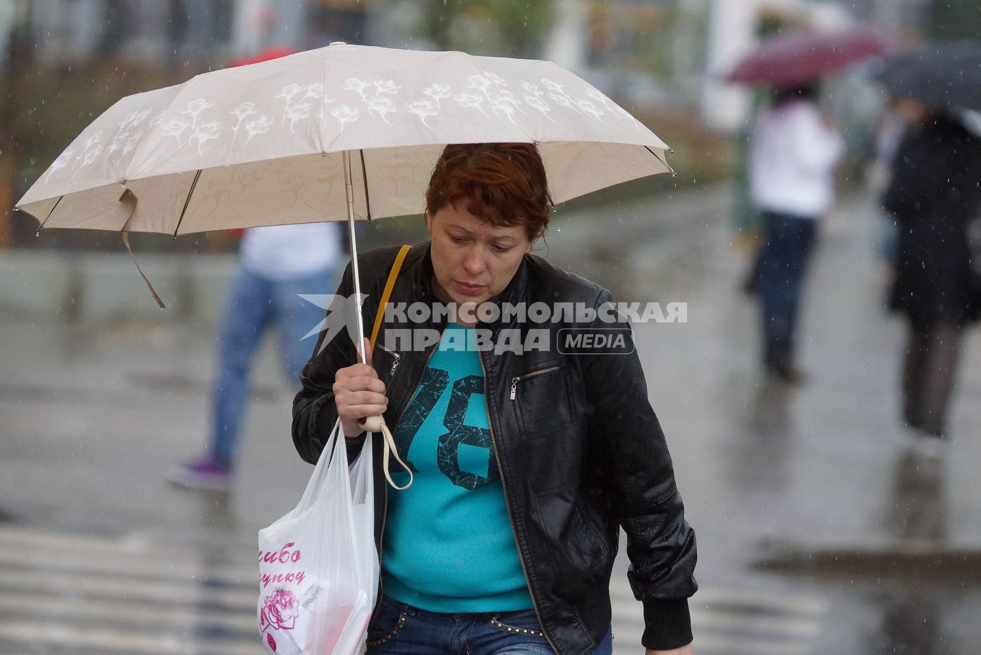женщина под зонтом переходит дорогу во время дождя