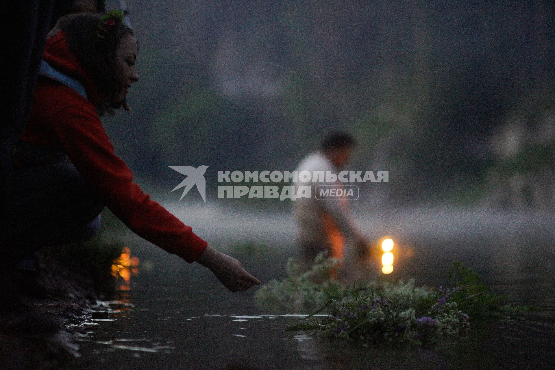 Девушкаво время  празднования дня Ивана Купала спускает на воду венок из цветов