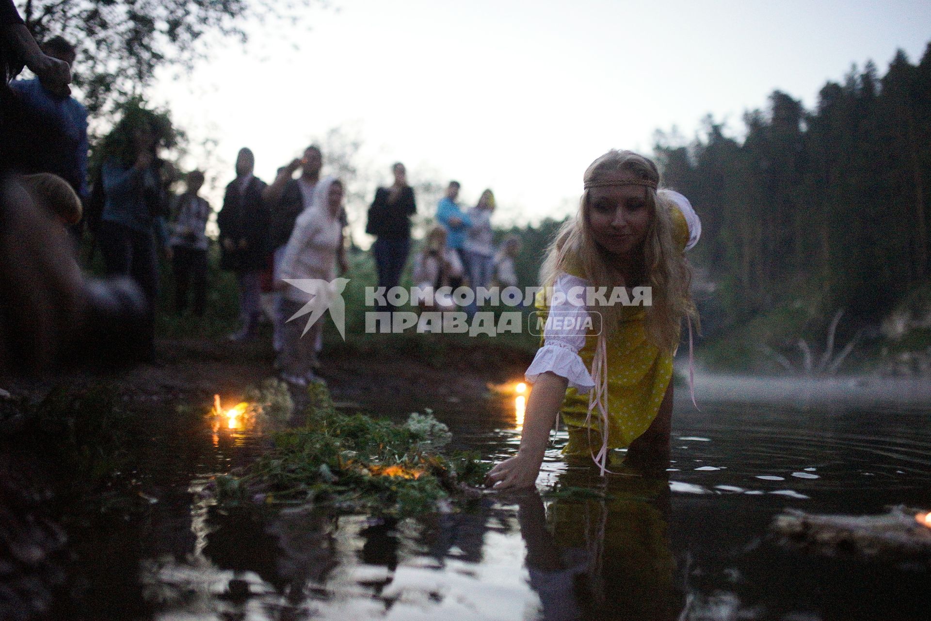 Участница празднования дня Ивана Купала спускает на воду венок