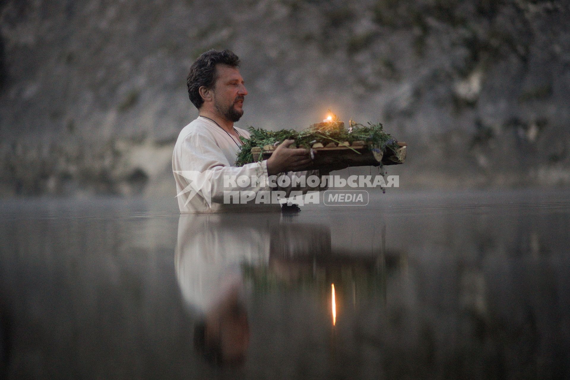Участник празднования дня Ивана Купала стоят с венками в руках, по грудь в воде