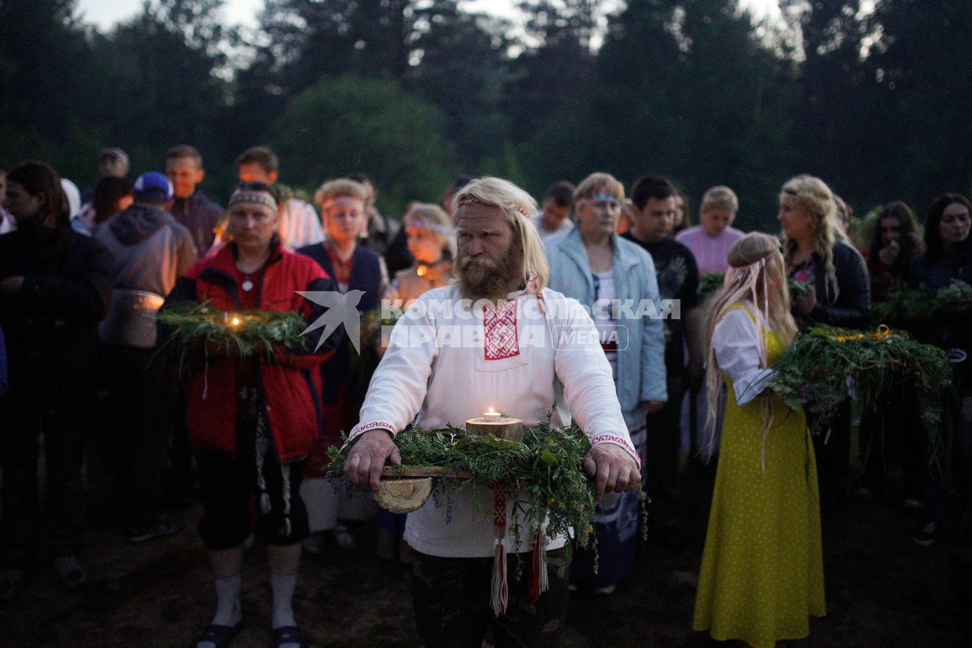 Участники празднования дня Ивана Купала стоят с венками в руках, перед их спуском на воду