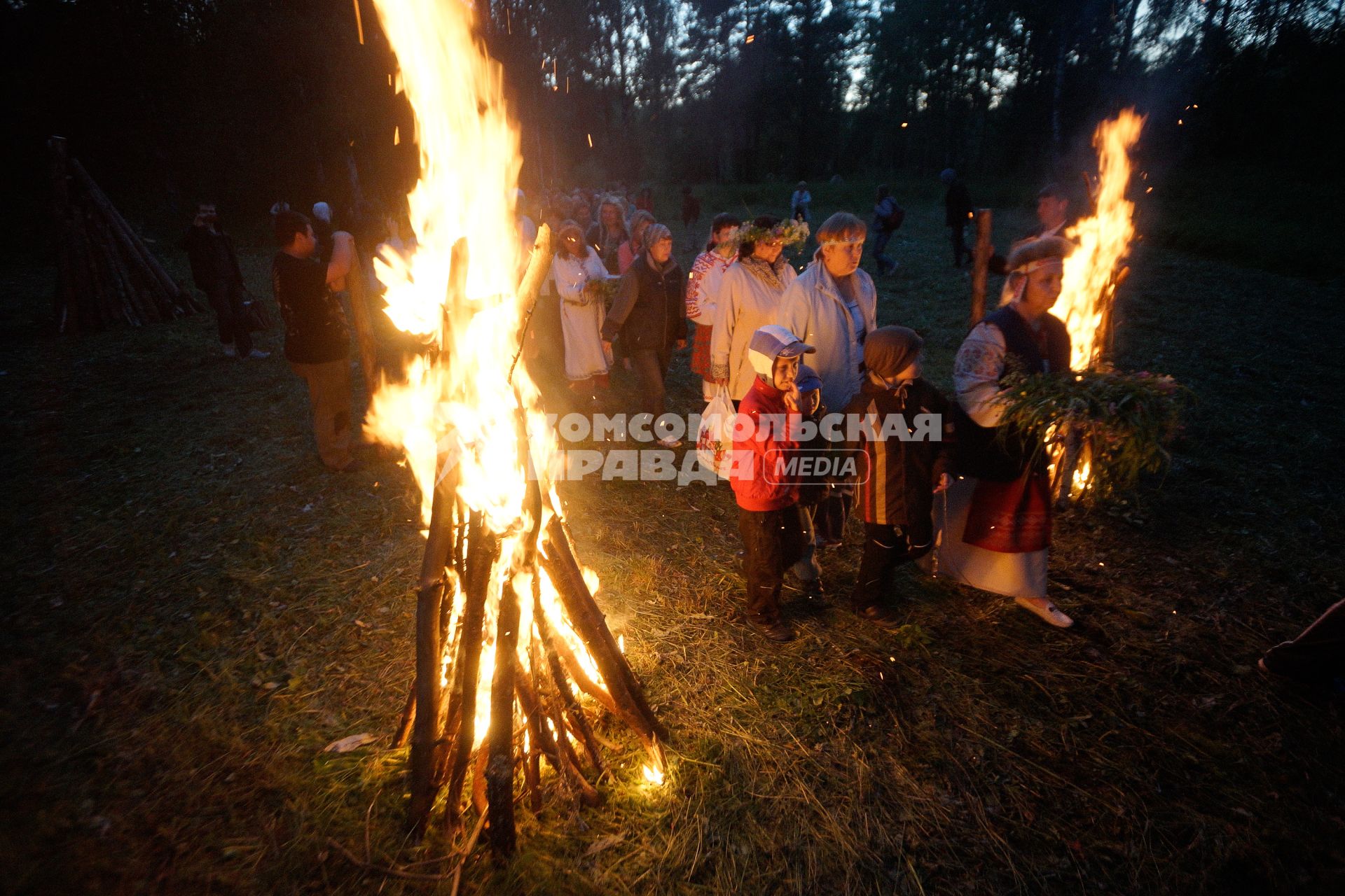 Участники празднования дня Ивана Купала во время обряда очищения огнем проходят между двух больших костров