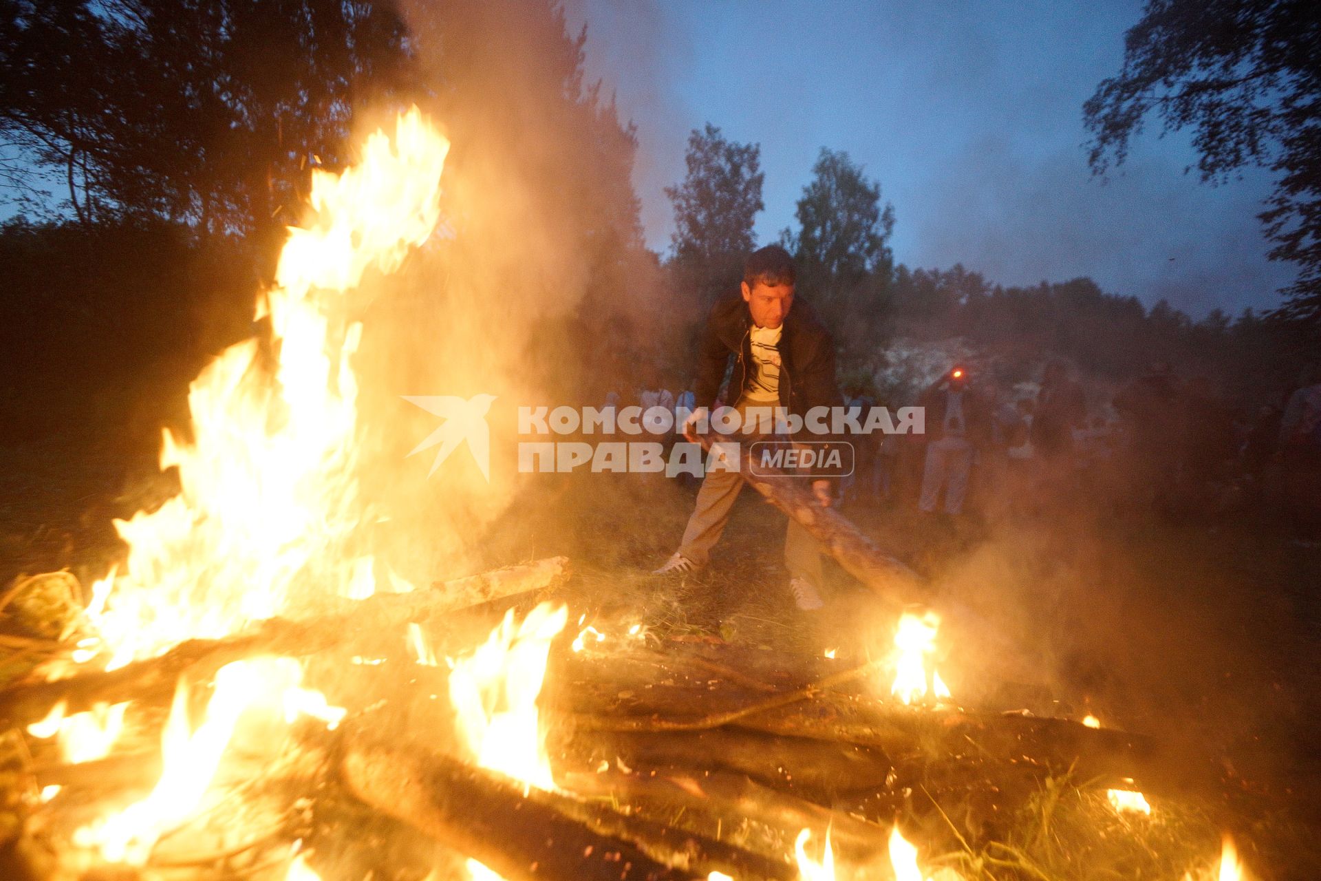 Участники празднования дня Ивана Купала во время обряда очищения огнем соединяют два больших костра