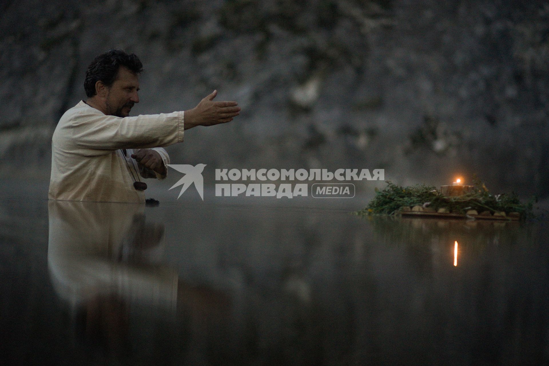 Участник празднования дня Ивана Купала стоят с венками в руках, по грудь в воде