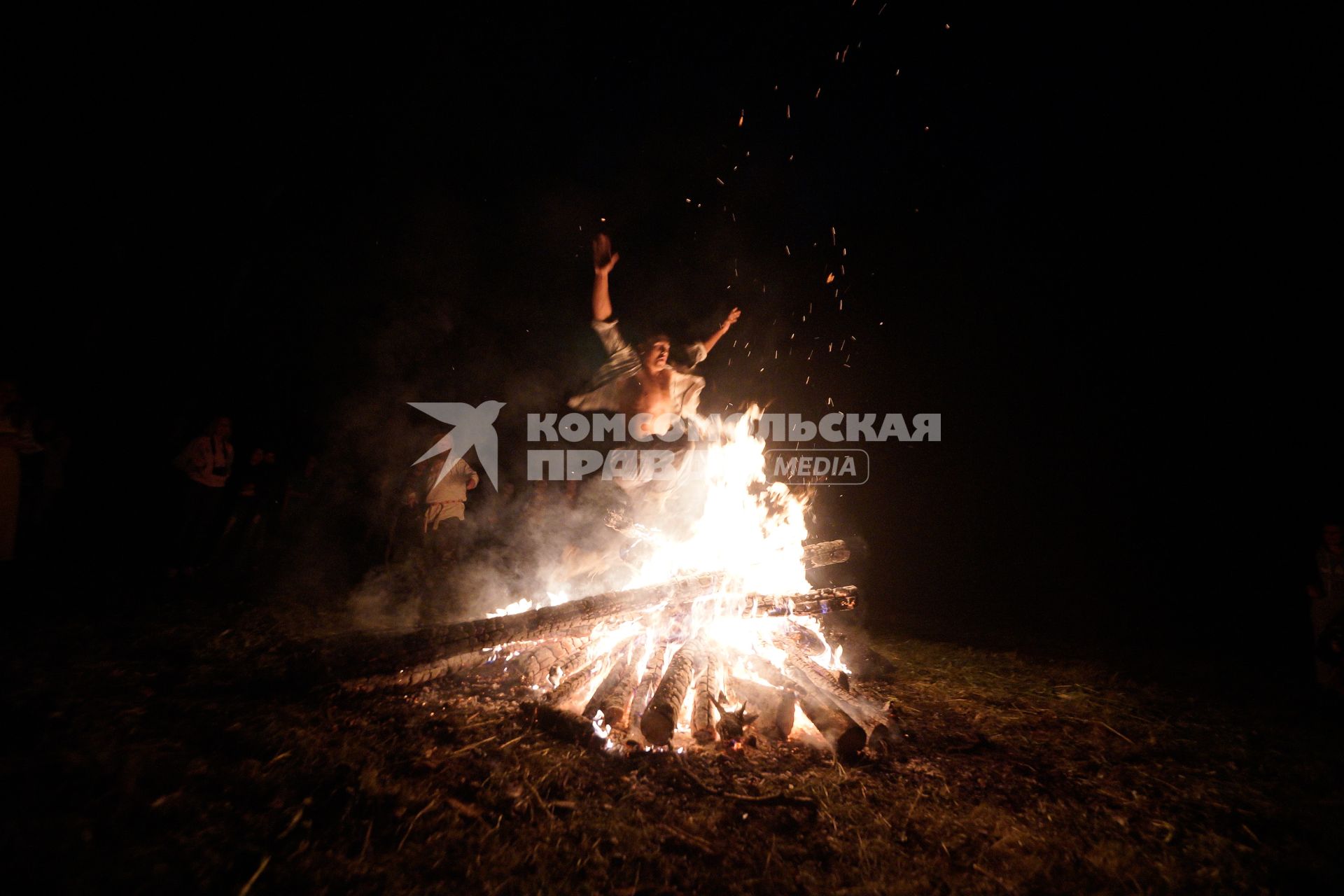 Участник празднования дня Ивана Купала прыгает через большой костер