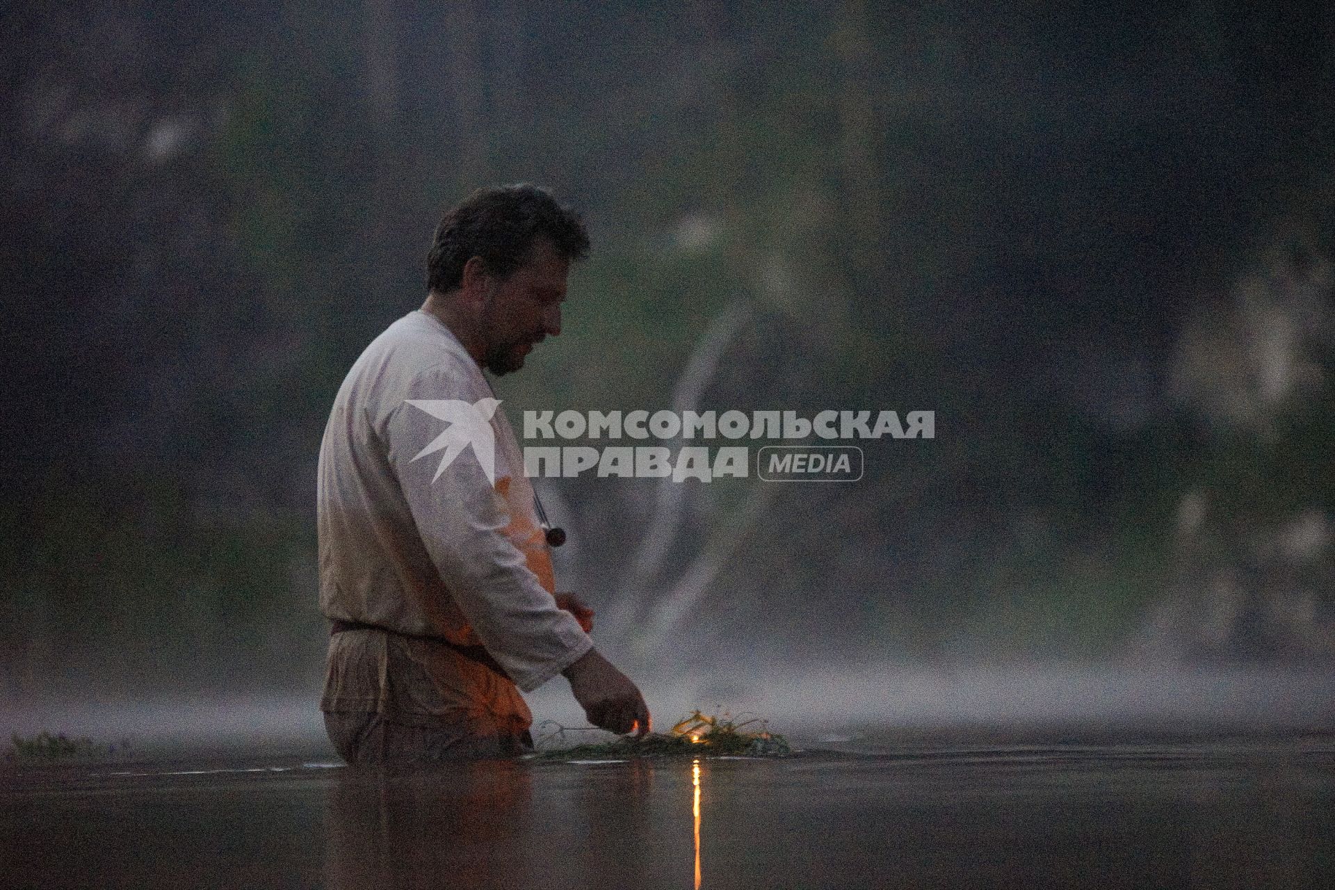 Участник празднования дня Ивана Купала стоят с венками в руках, по пояс в воде