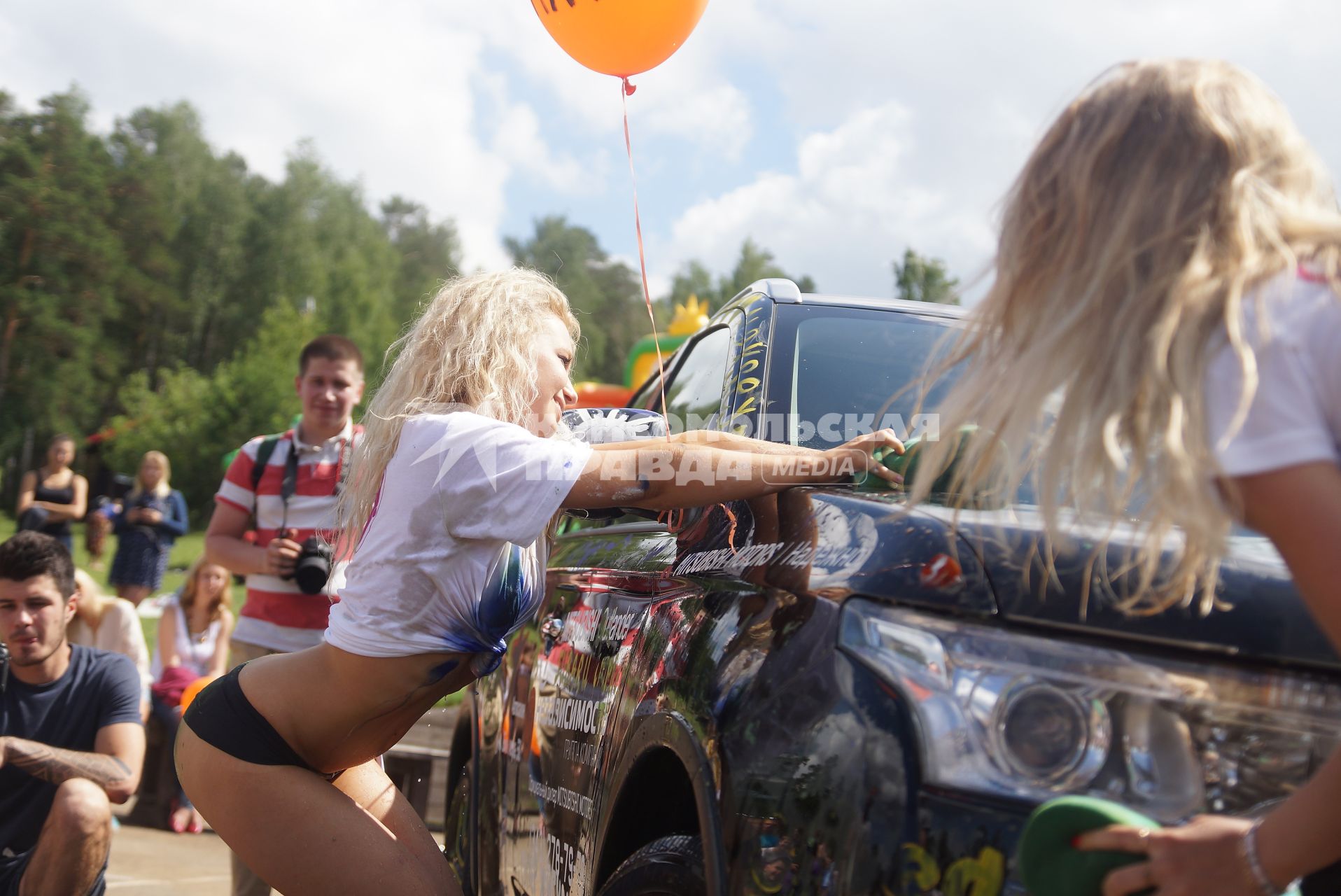 Девушки в белых майках моют раскрашеную машину во время проведения конкурса \"мокрые майки\" в Екатеринбурге