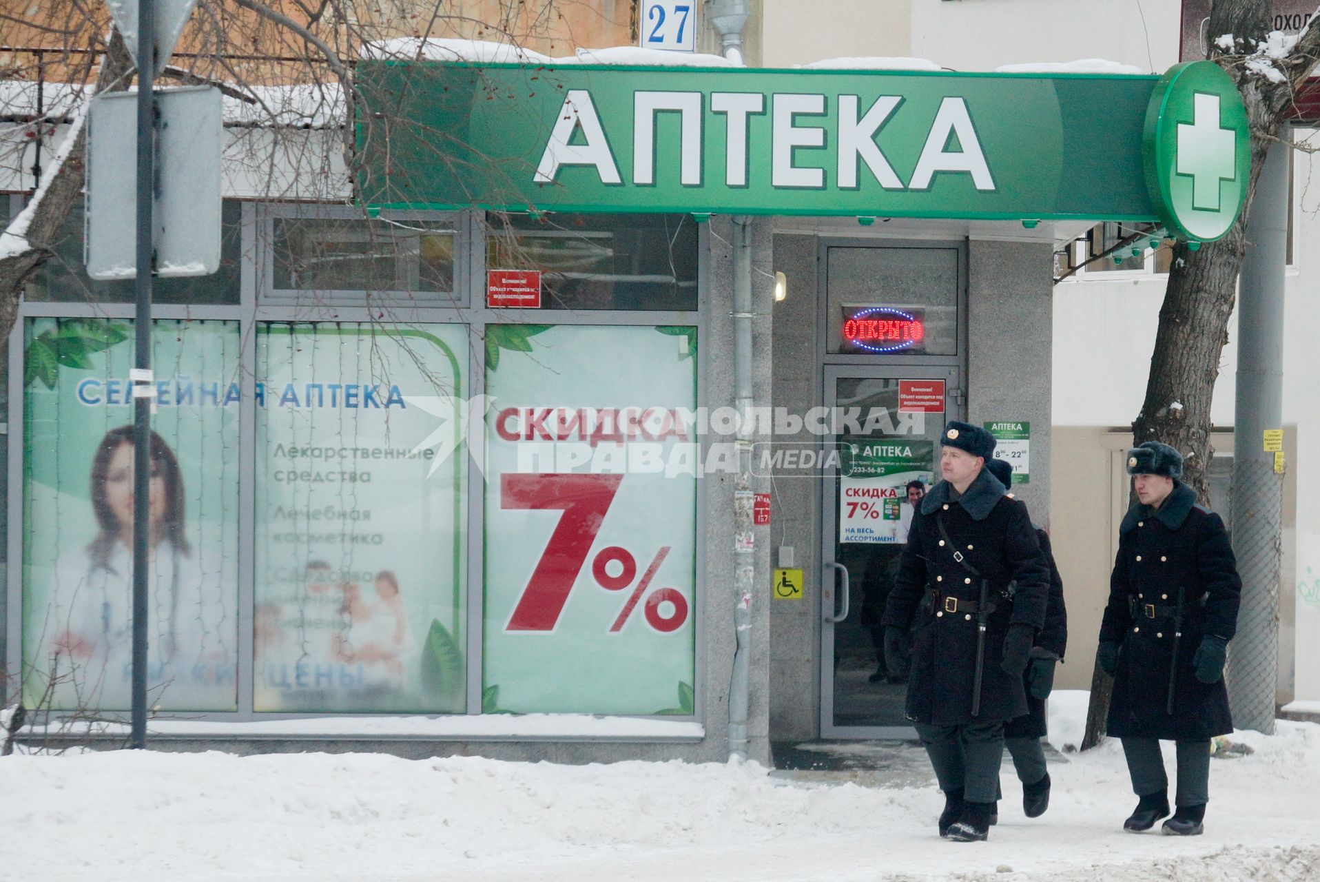 Полицейские патруль из трех человек идут мимо аптреки