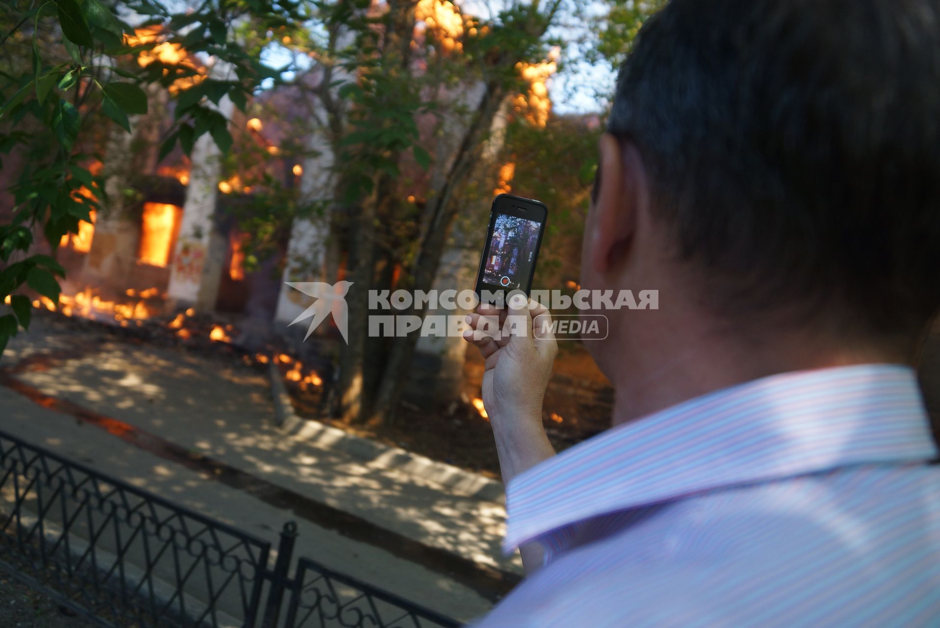Мужчина снимает пожар в доме на сотовый телефон